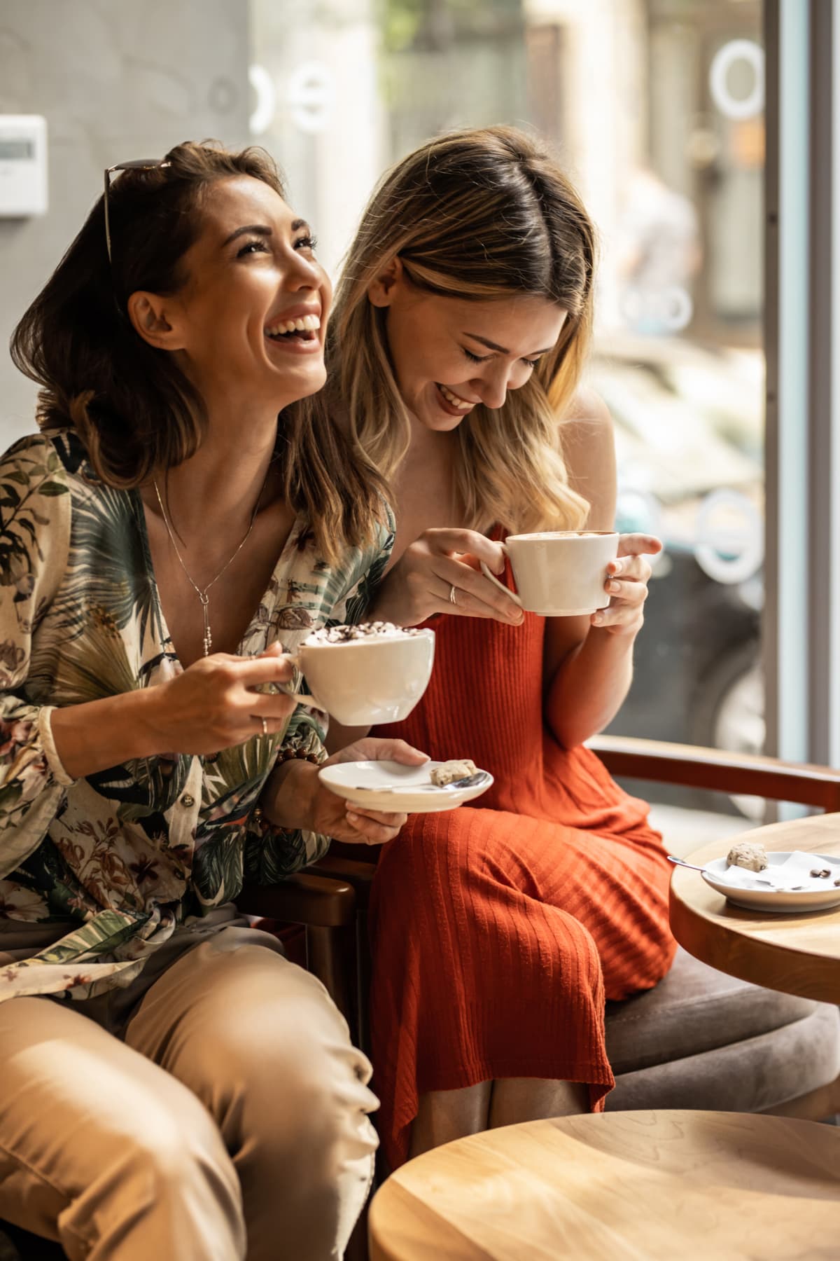 Two friends drinking coffee and laughing