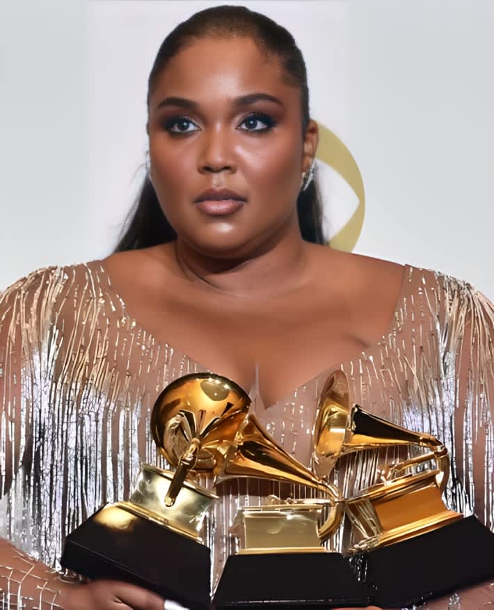 A stunned Lizzo holds three of her Grammy awards close to her chest