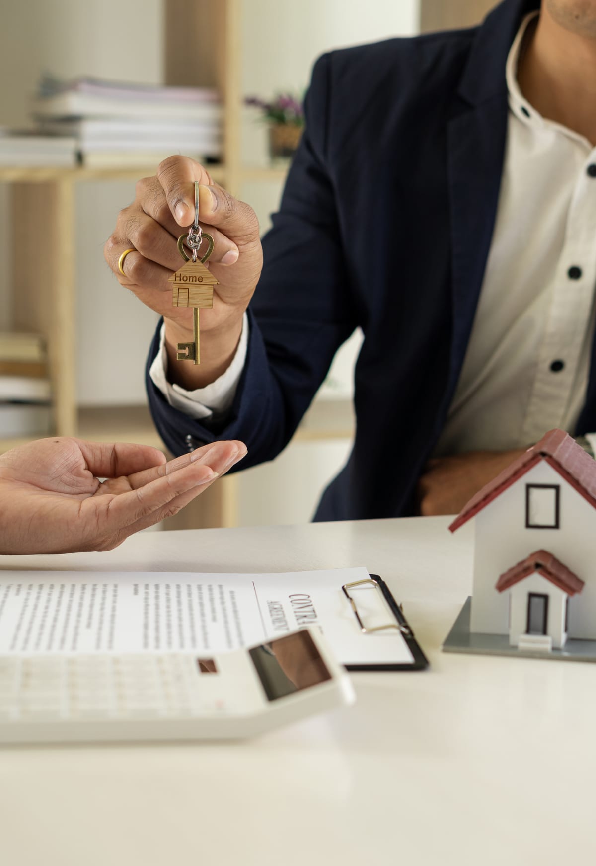 Real estate agent handing a home-shaped key to a client