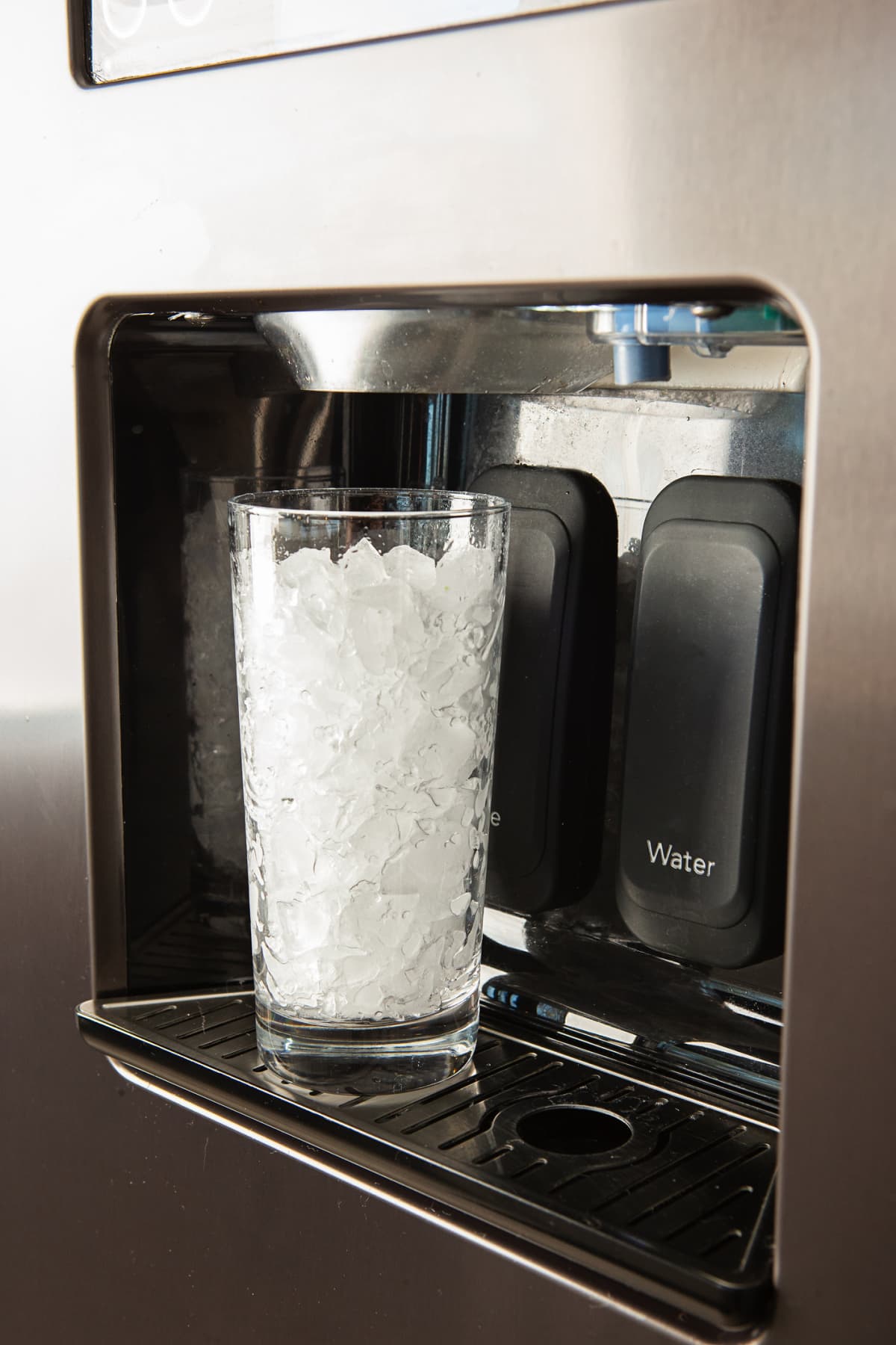 Ice maker dispensing ice into a glass.