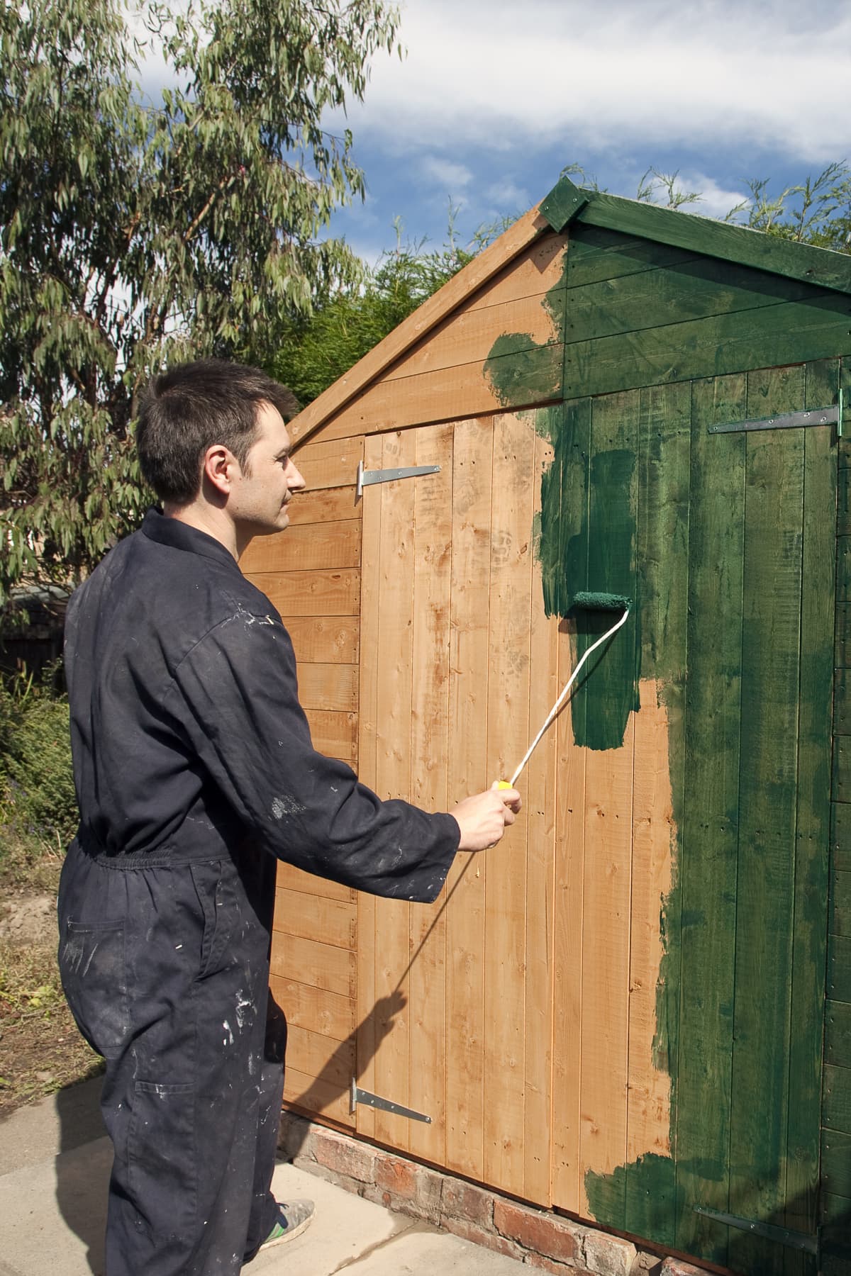 Man painting a garden shed.