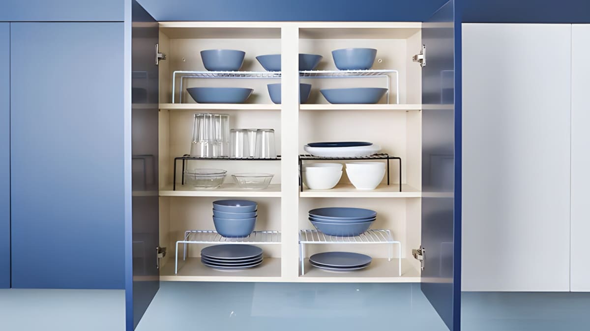 Organized shelf risers in a kitchen cabinet.