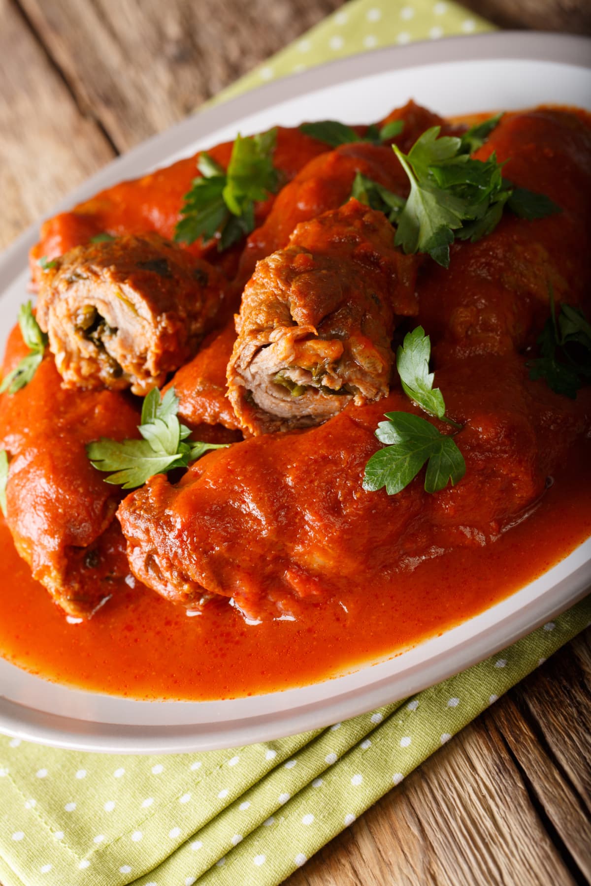 close-up of italian Braciole - beef steak rolls filled with sliced prosciutto, grated parmesan cheese and parsley, cooked with marinara sauce in a skillet, view from above