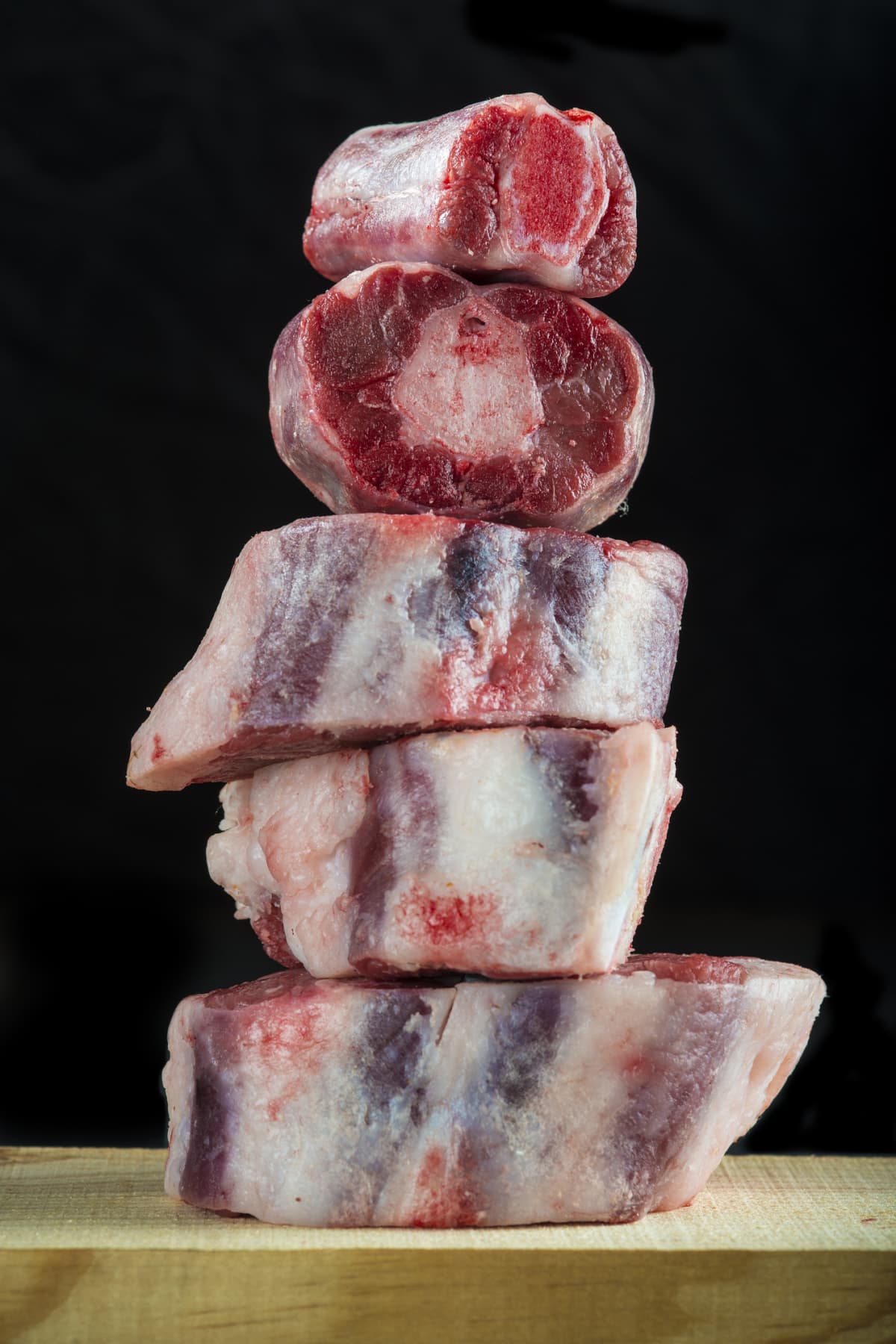 Fresh and raw oxtail cut on the cutting board isolated on a black background