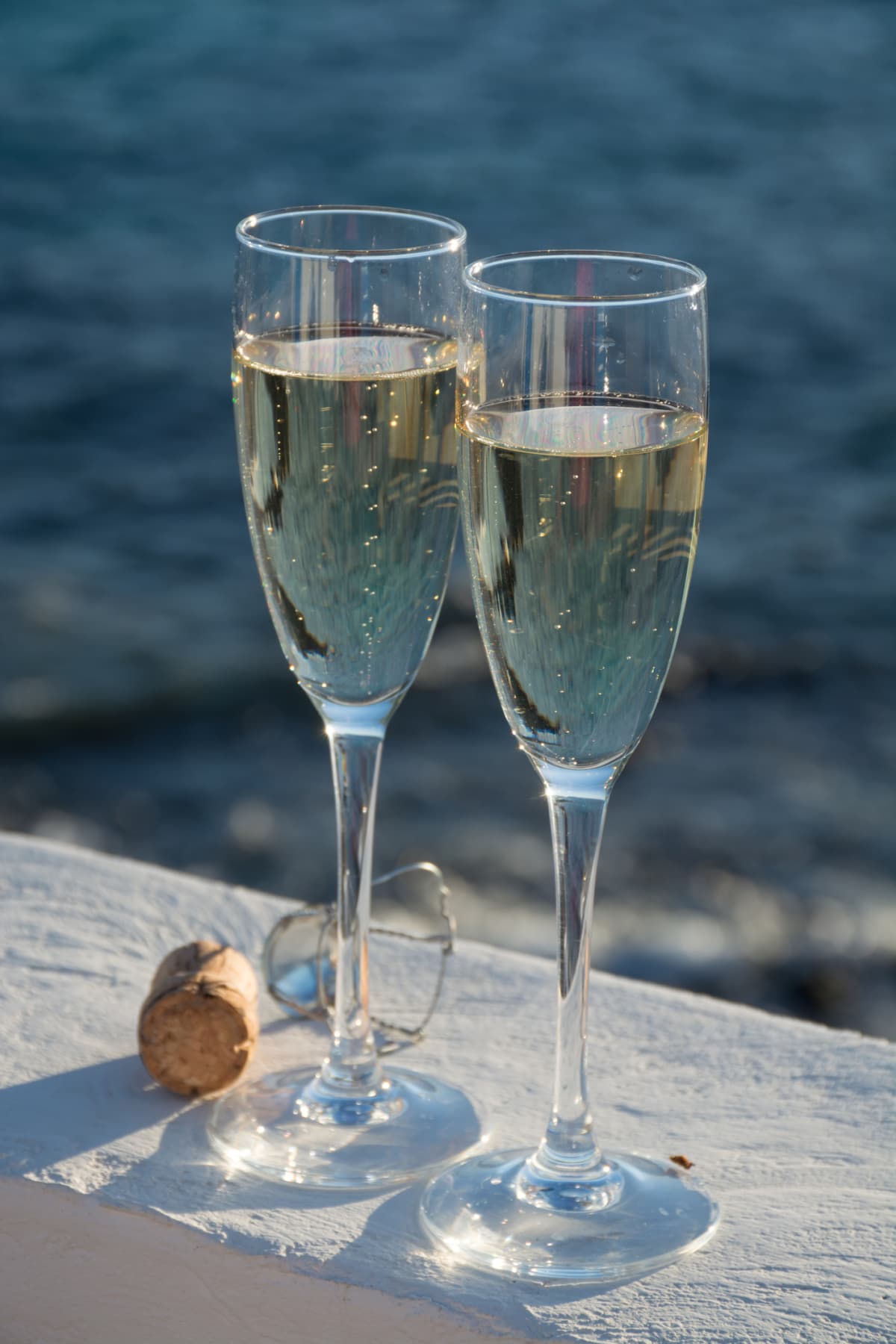 Two glasses of cold white champagne or cava sparkling wine served on the white sandy tropical beach, luxury resort with sea view, romantic vacation