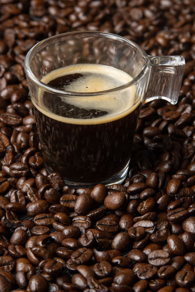 A mug of coffee atop coffee beans