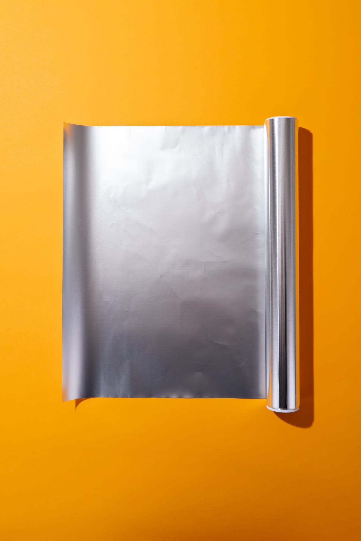 A roll of aluminum foil on an orange background