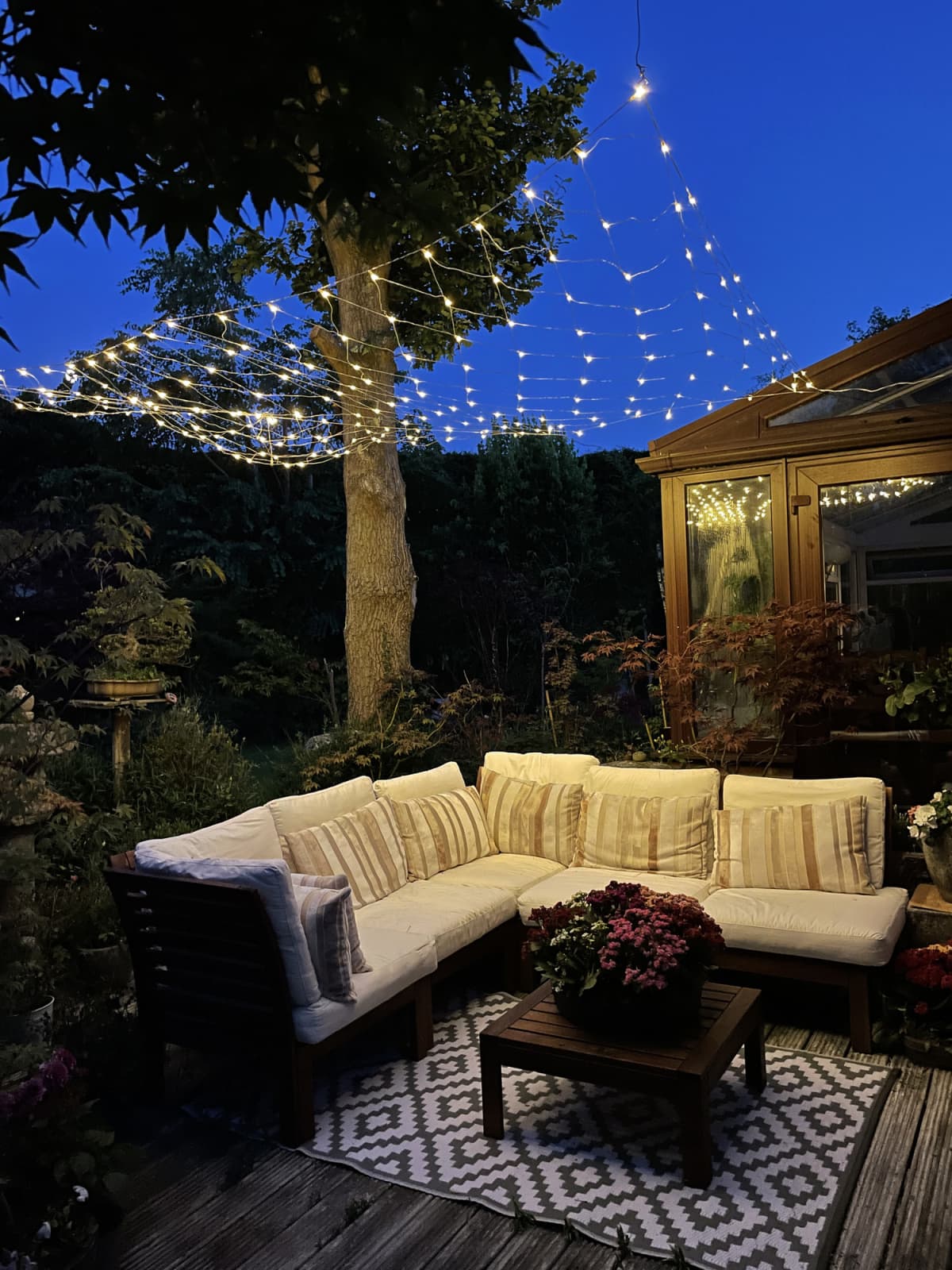 An outdoor lounging area illuminated by string fairy lights during nighttime