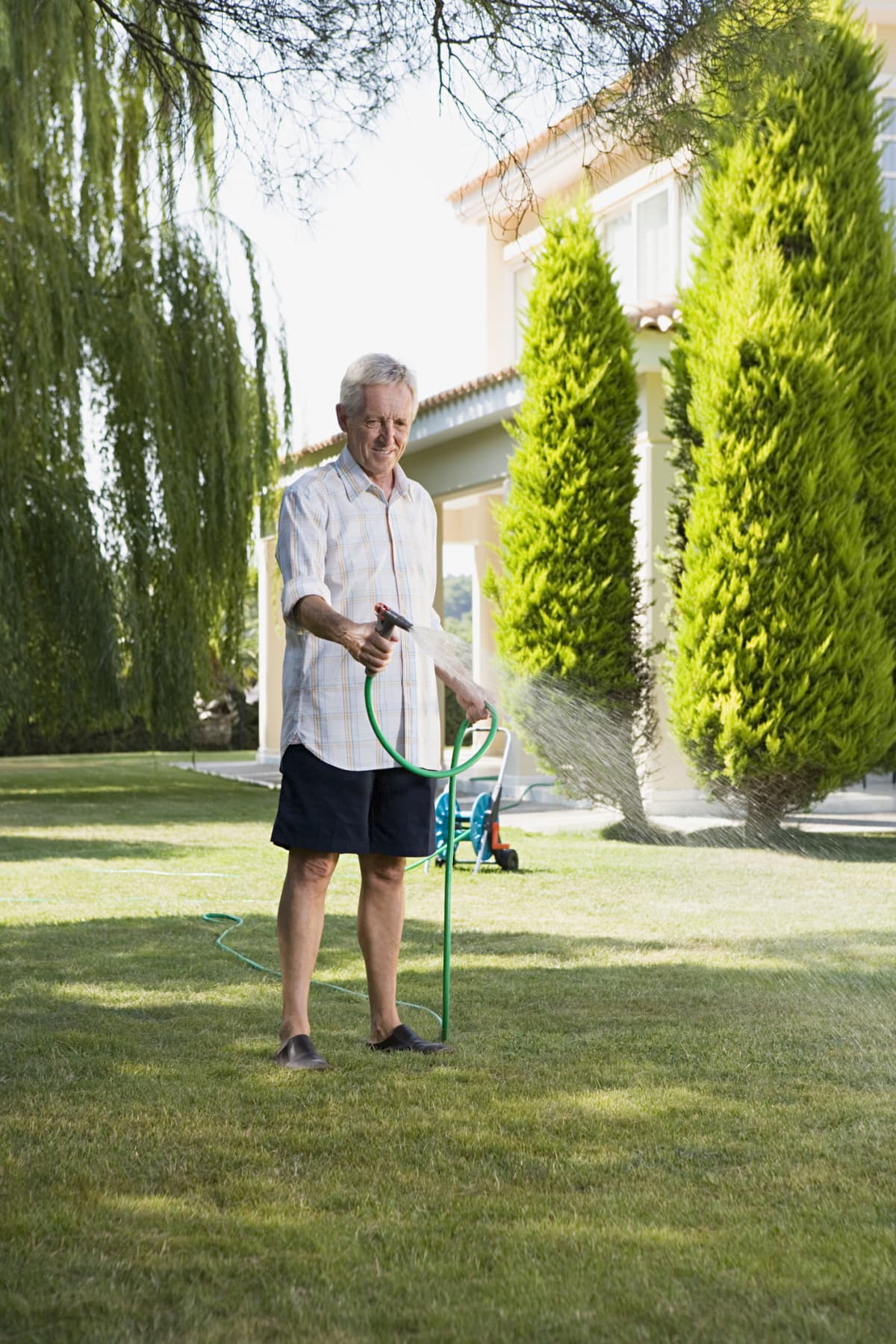 An elderly adult applying liquid iron to his lawn