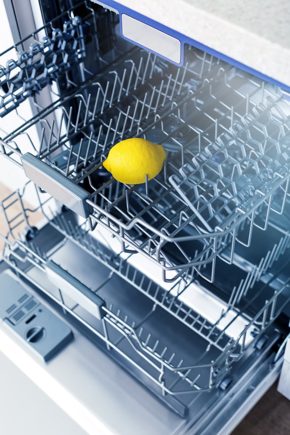 Empty dishwasher with fresh yellow lemon on shelf, aroma freshness care concept, clean equipment,  home appliance dishwashing machine in kitchen interior, no people