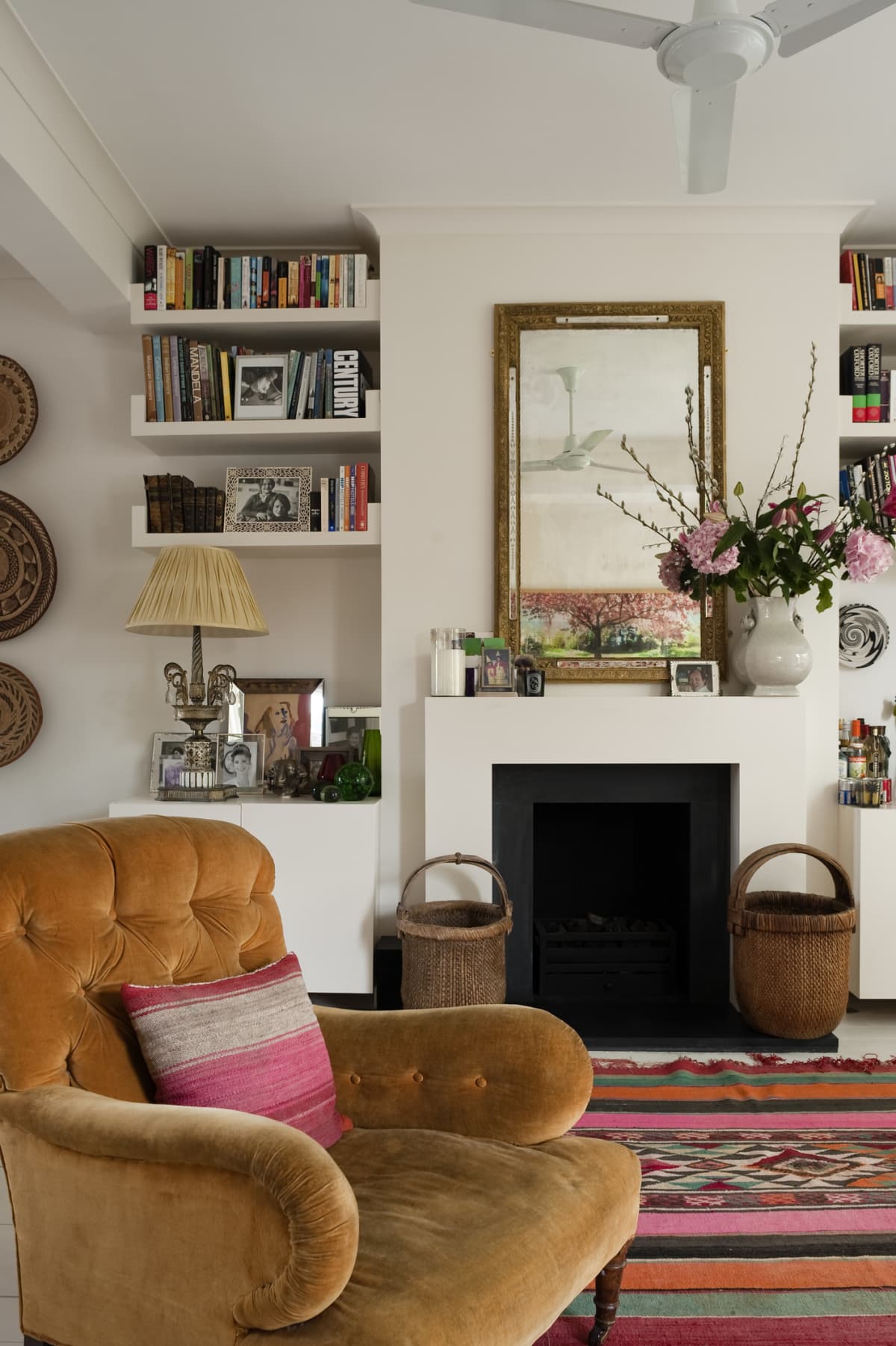 Brown buttoned armchair from George Smith in white living room with moroccan rug and fireplace