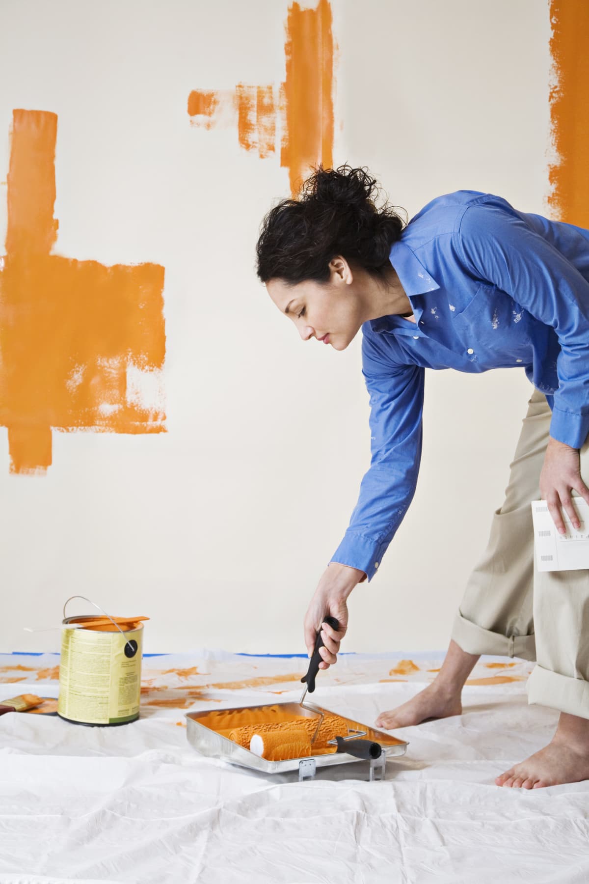 a woman painting the wall orange