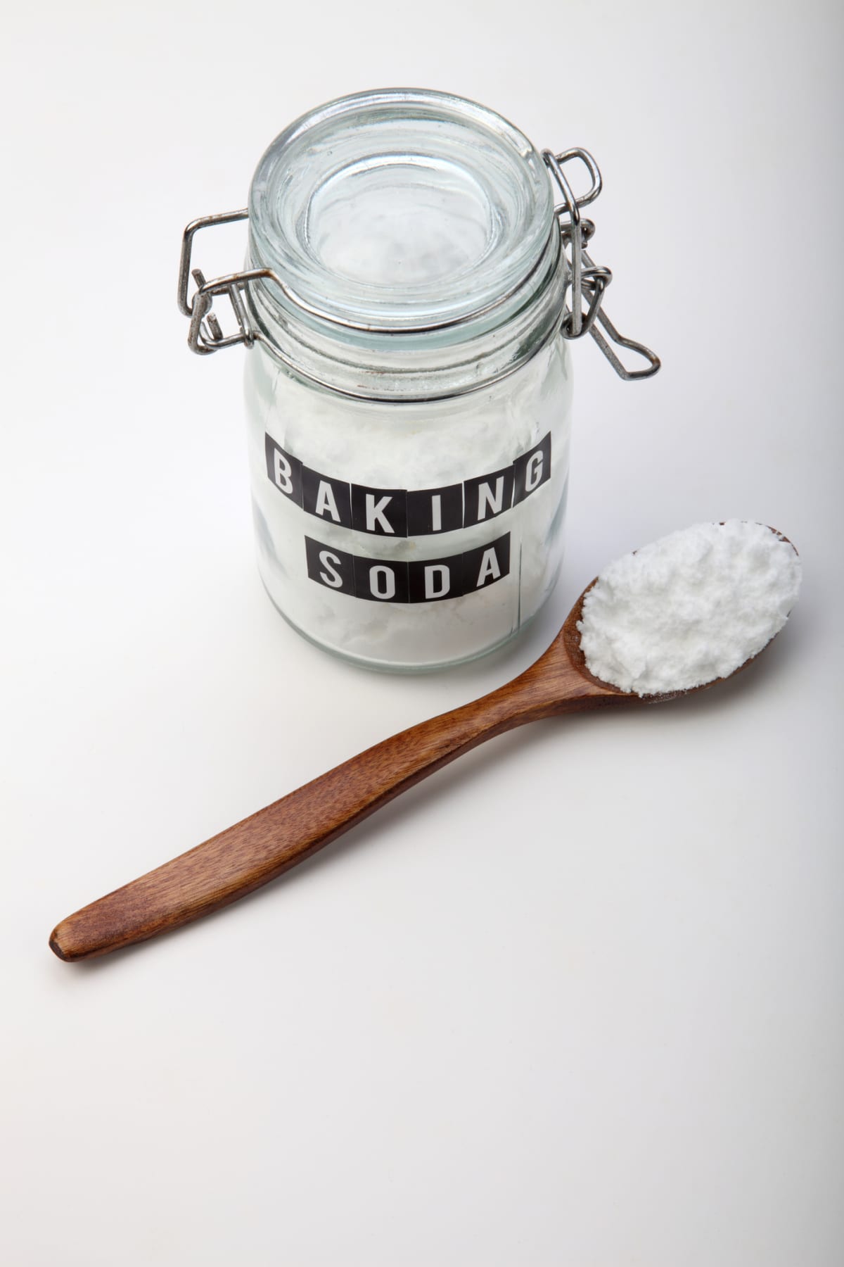 A jar of baking soda and a wooden spoon