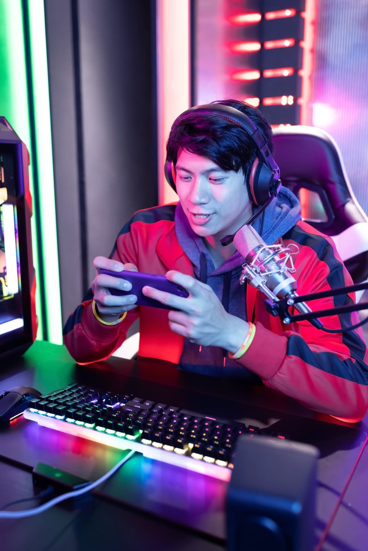 Young Asian Handsome Pro Gamer wearing headset is playing on a gaming phone during live stream