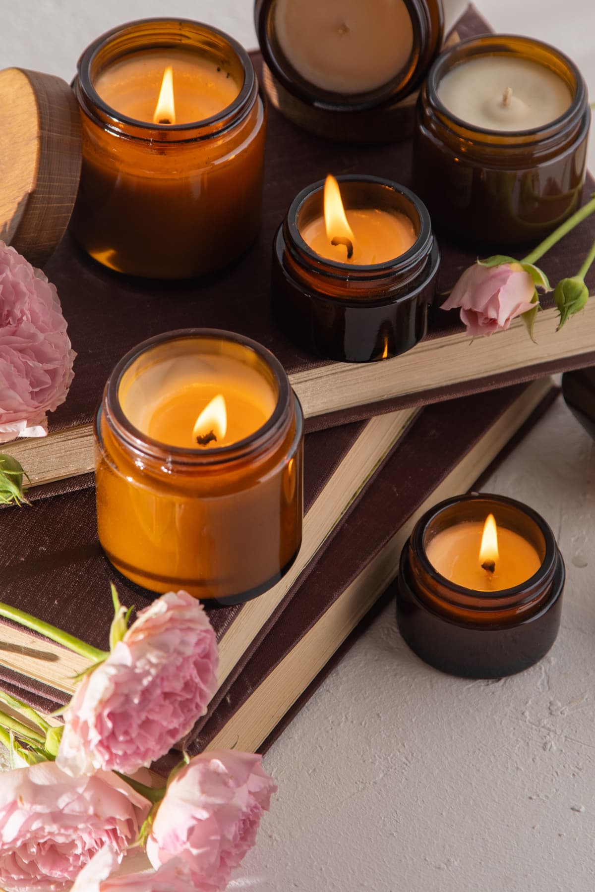 An artful arrangement of aromatic candles in brown glass jars, accompanied by roses