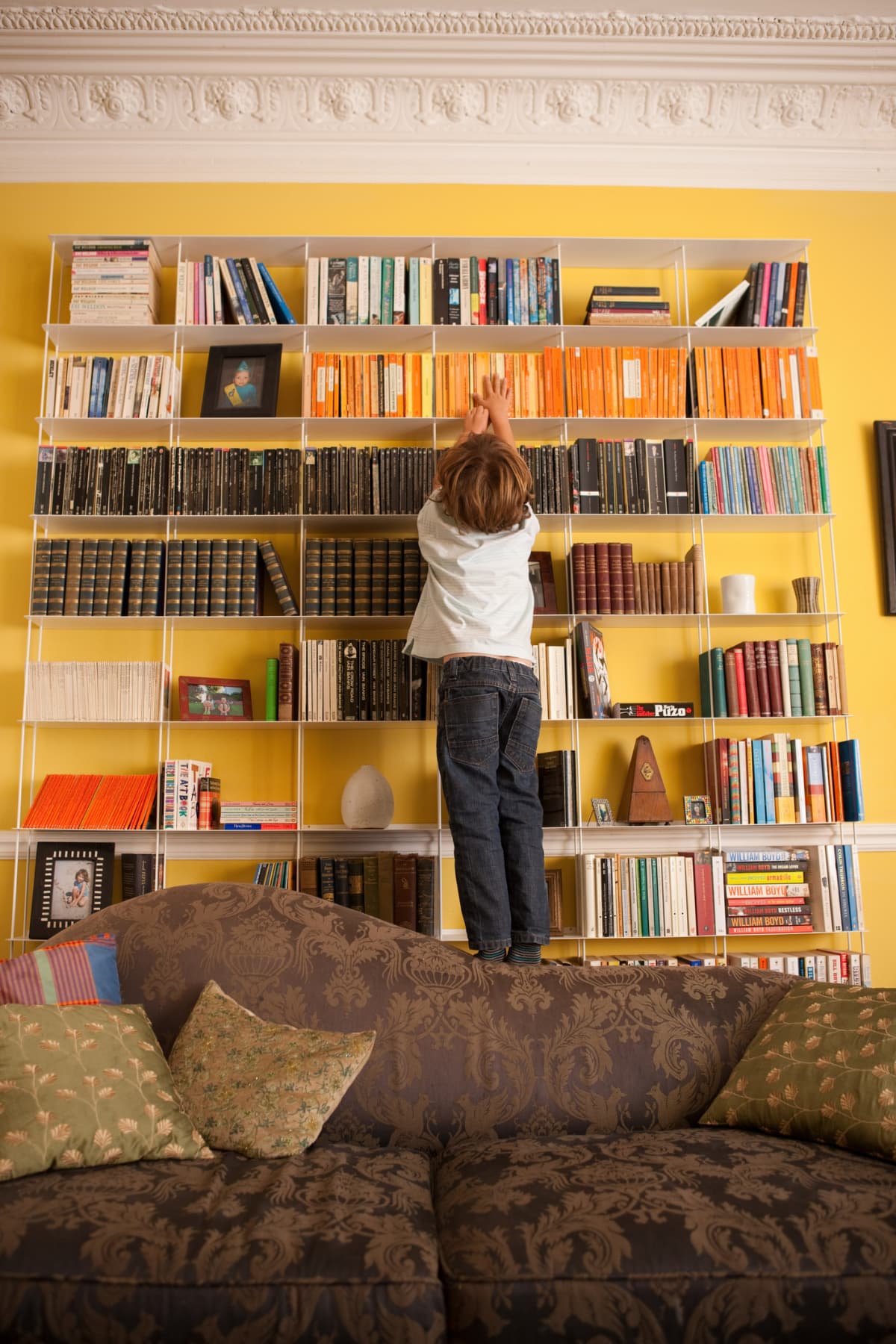 Boy reaching up towards a book on a shelf