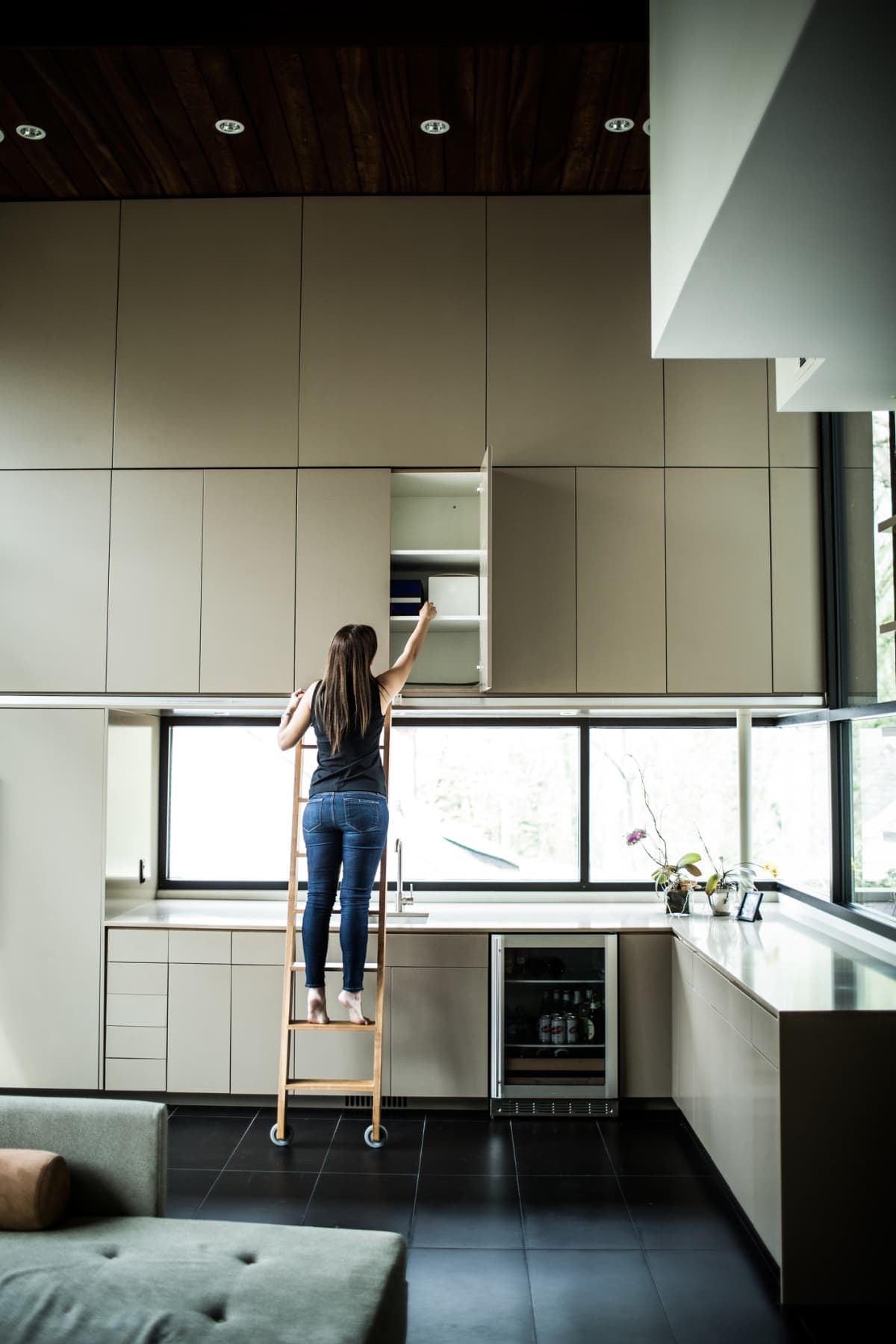 Woman on ladder looking through kitchen cabinets