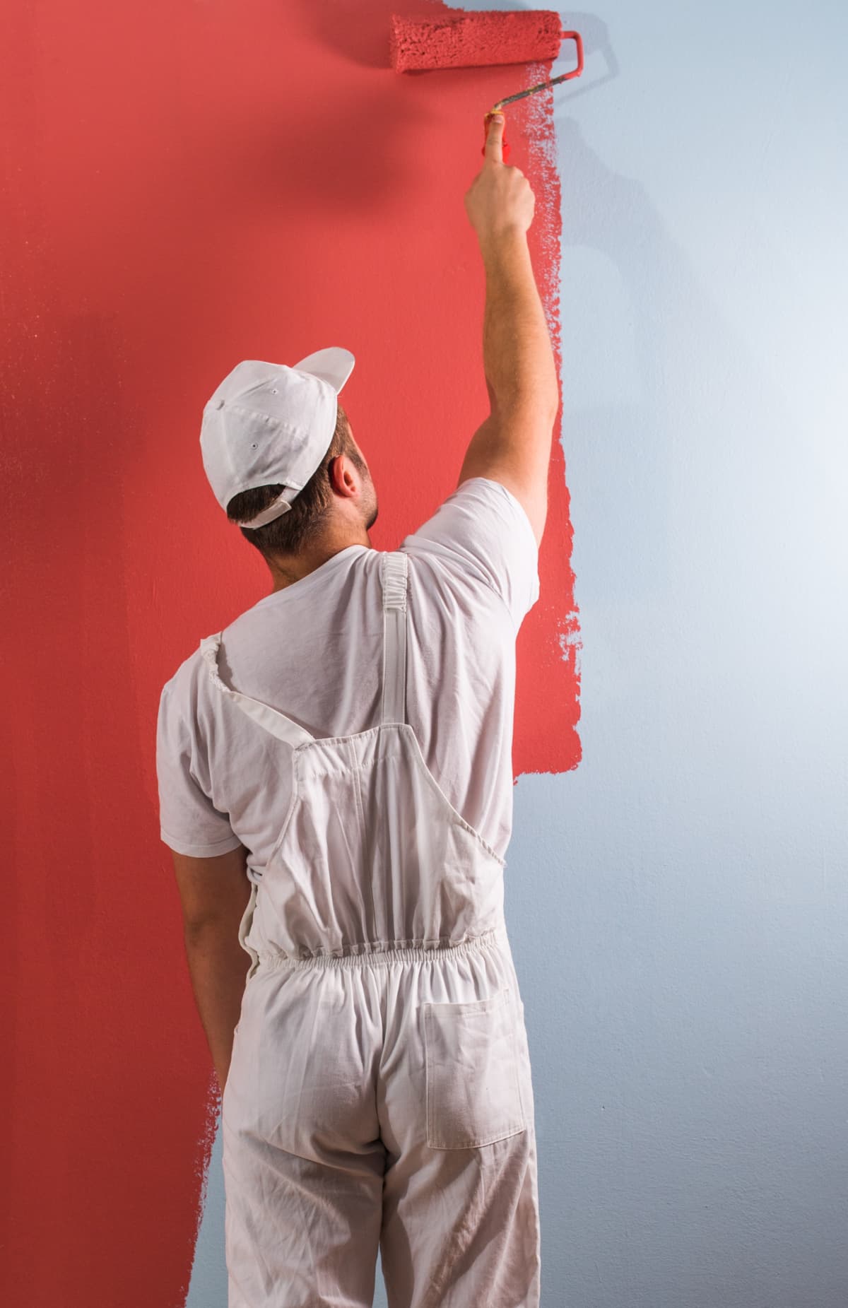 A man painting a wall using a paint roller