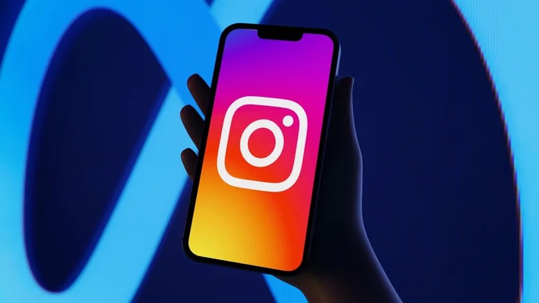 A hand holding a smartphone with the Instagram logo on the screen