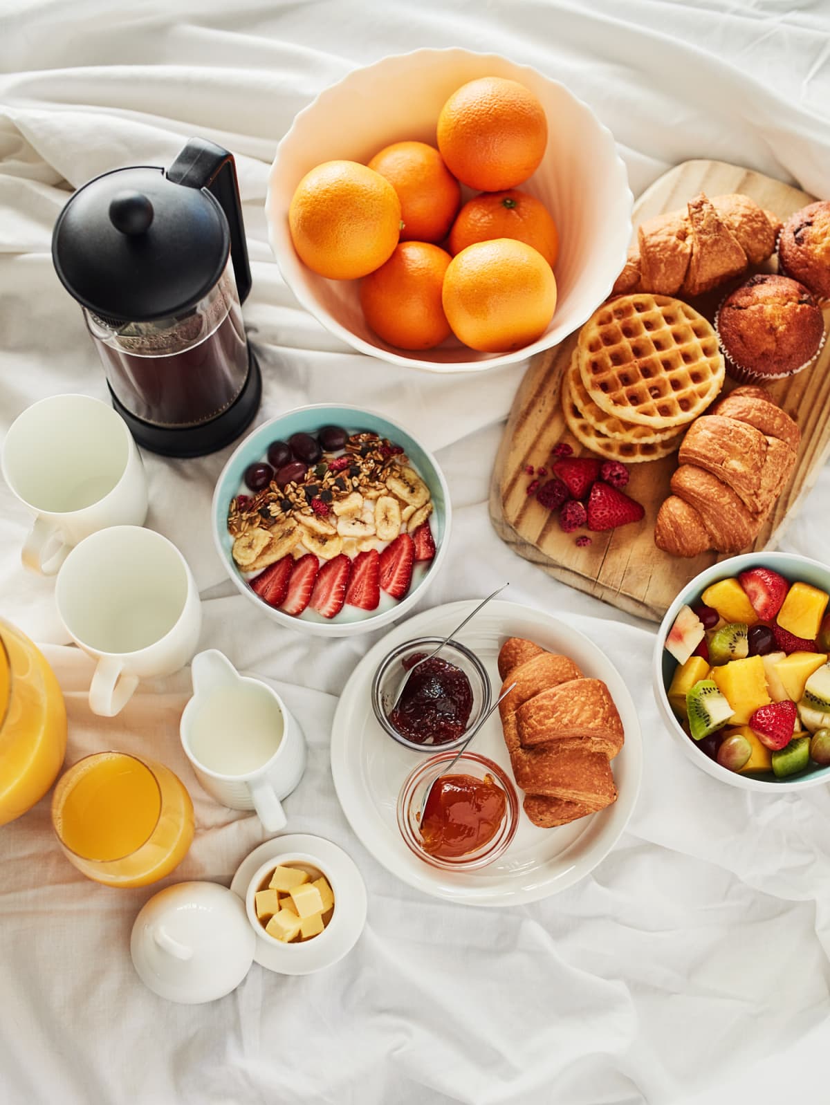 A delicious breakfast spread on a bed at home.