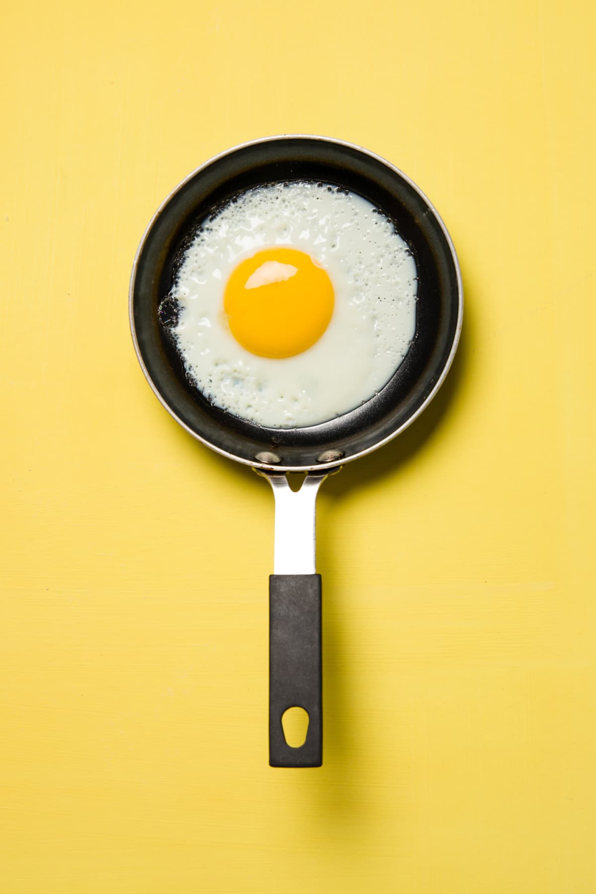 Fried egg in a pan with yellow background