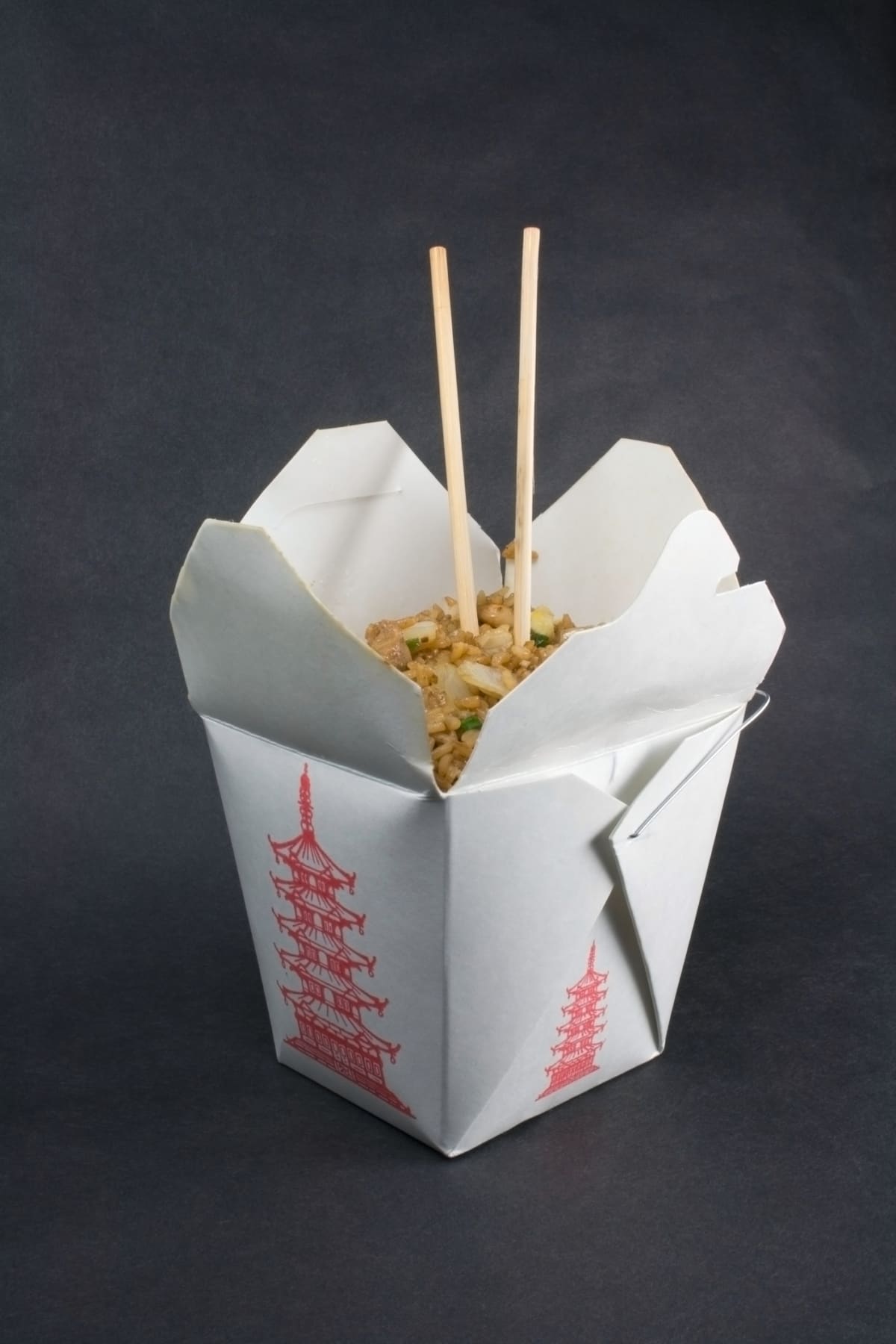 Fried rice in a chinese take out food container with chopsticks.
