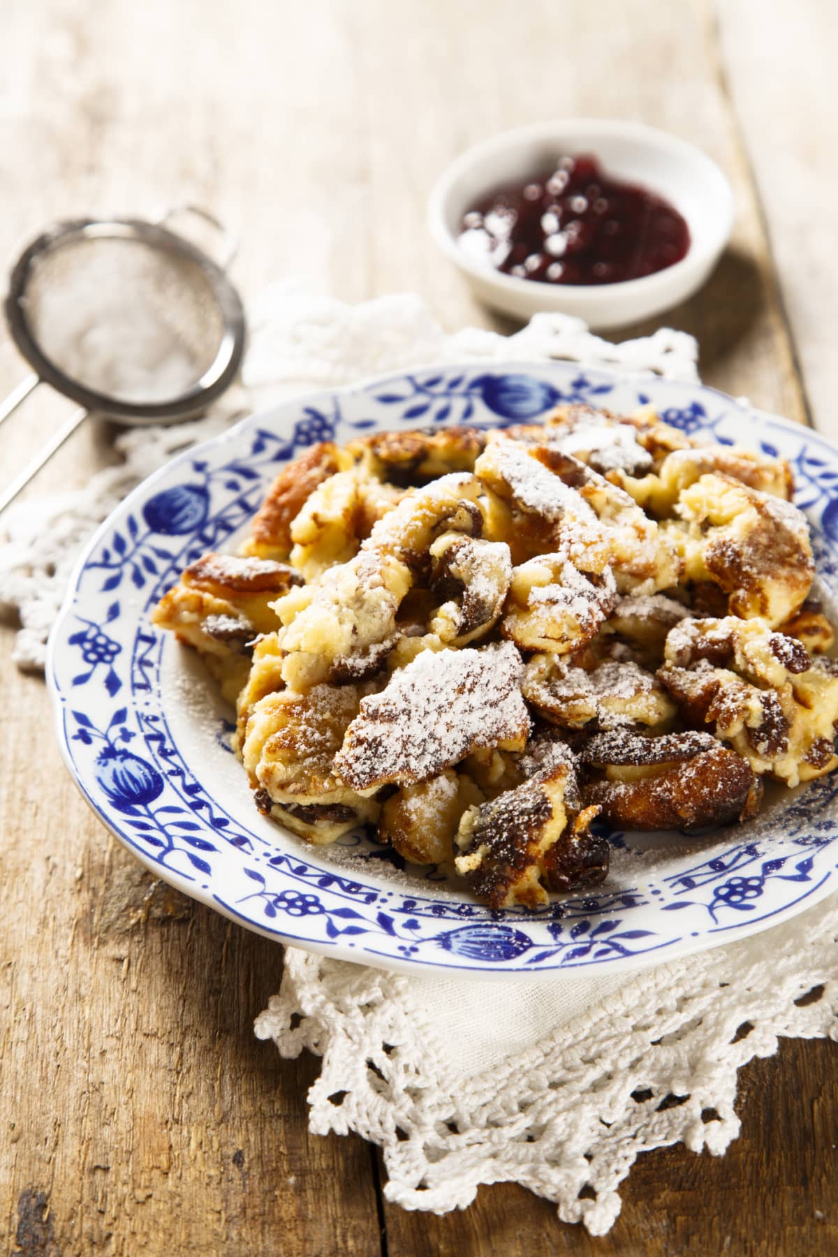 A top view of kaiserschmarrn with torn pancakes, cranberries jam, and apple puree on a table
