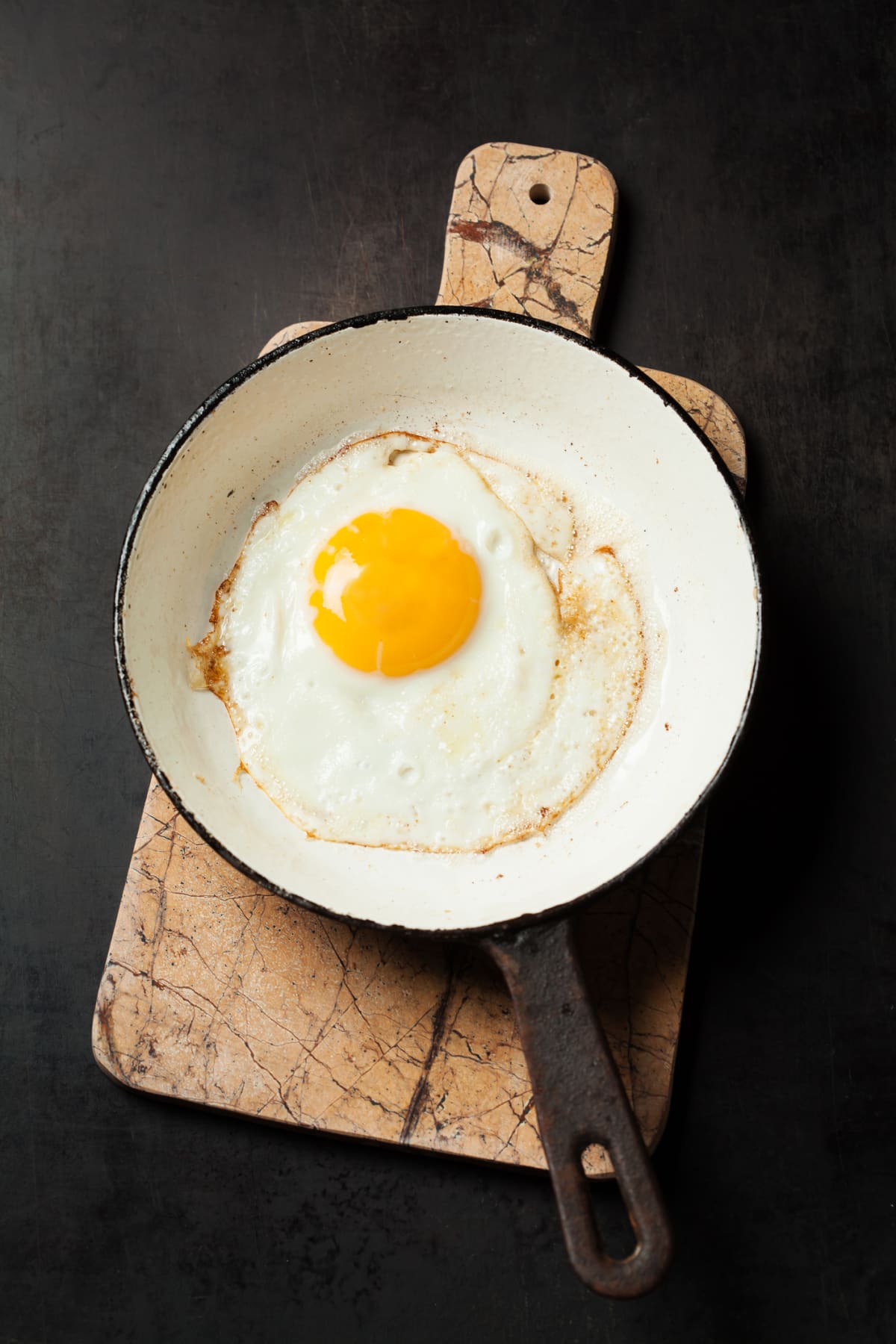 Fried egg in pan on cutting board