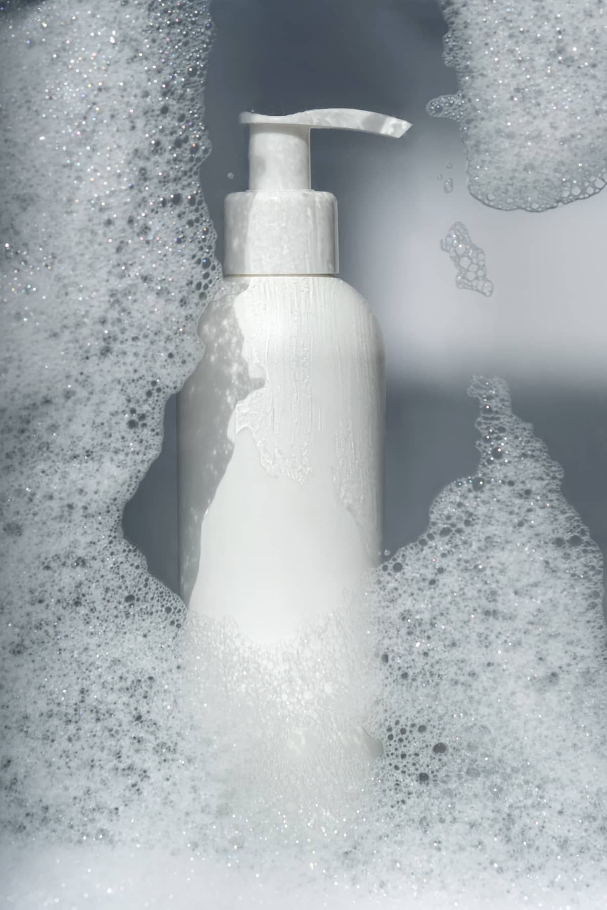 A bottle of gel or shampoo on a background of white foam. A perfect demonstration of the product and texture.