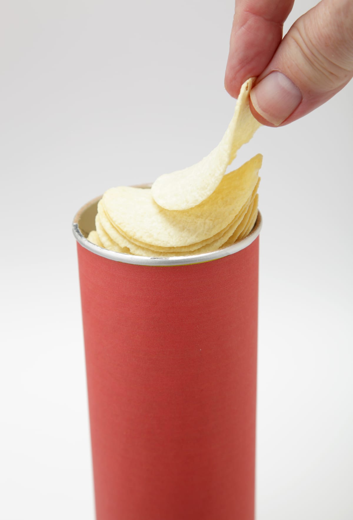 Selecting picking from Round Tube  of crisps pringles on plain background - not isolated