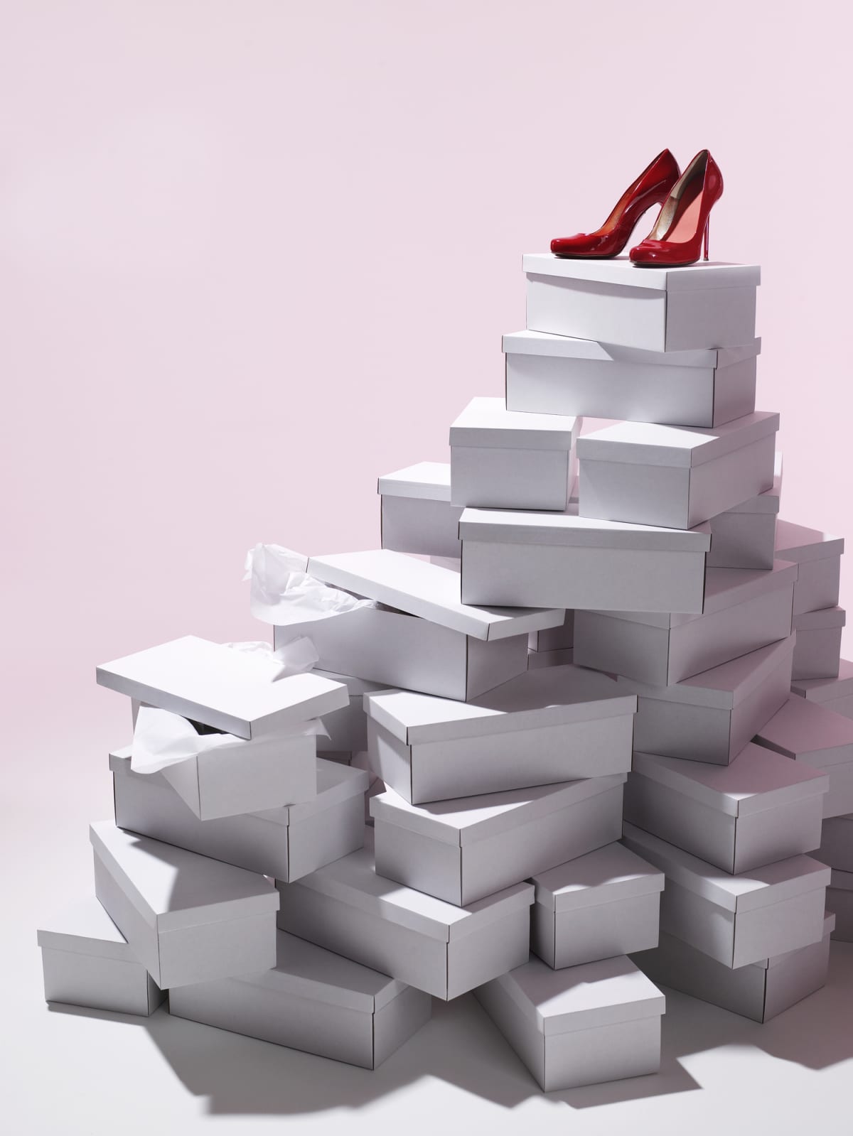 A pair of red shoes positioned atop a stack of shoe boxes