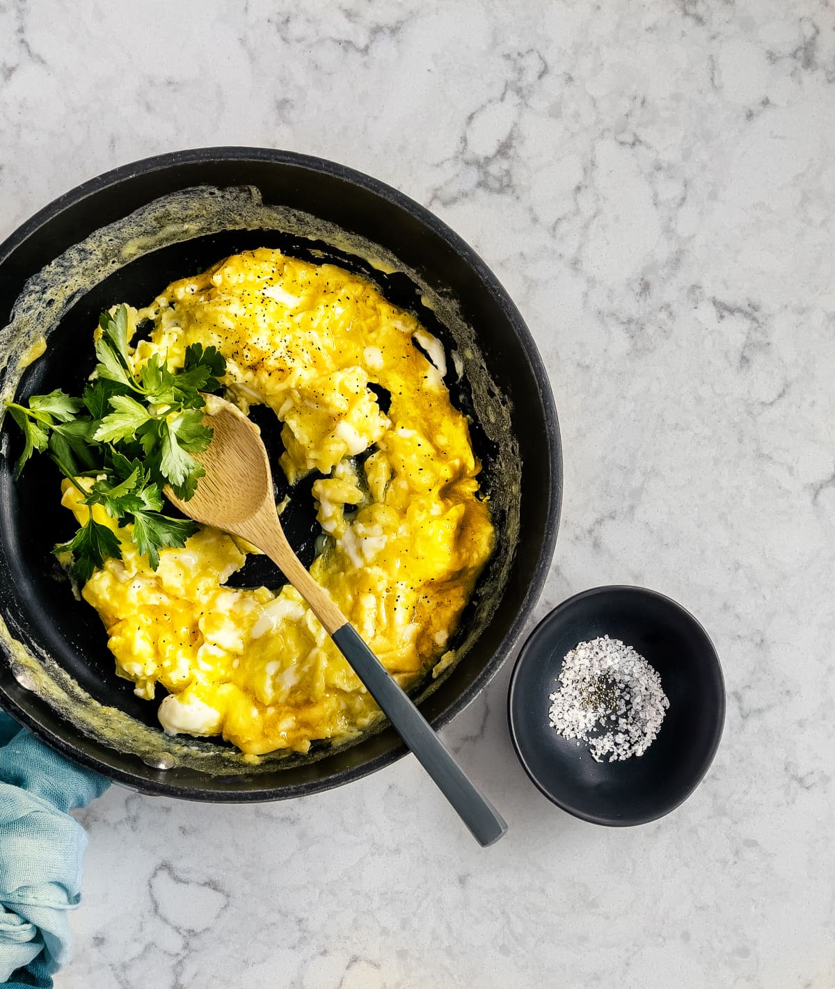 Scrambled eggs in a skillet on a white, marble background
