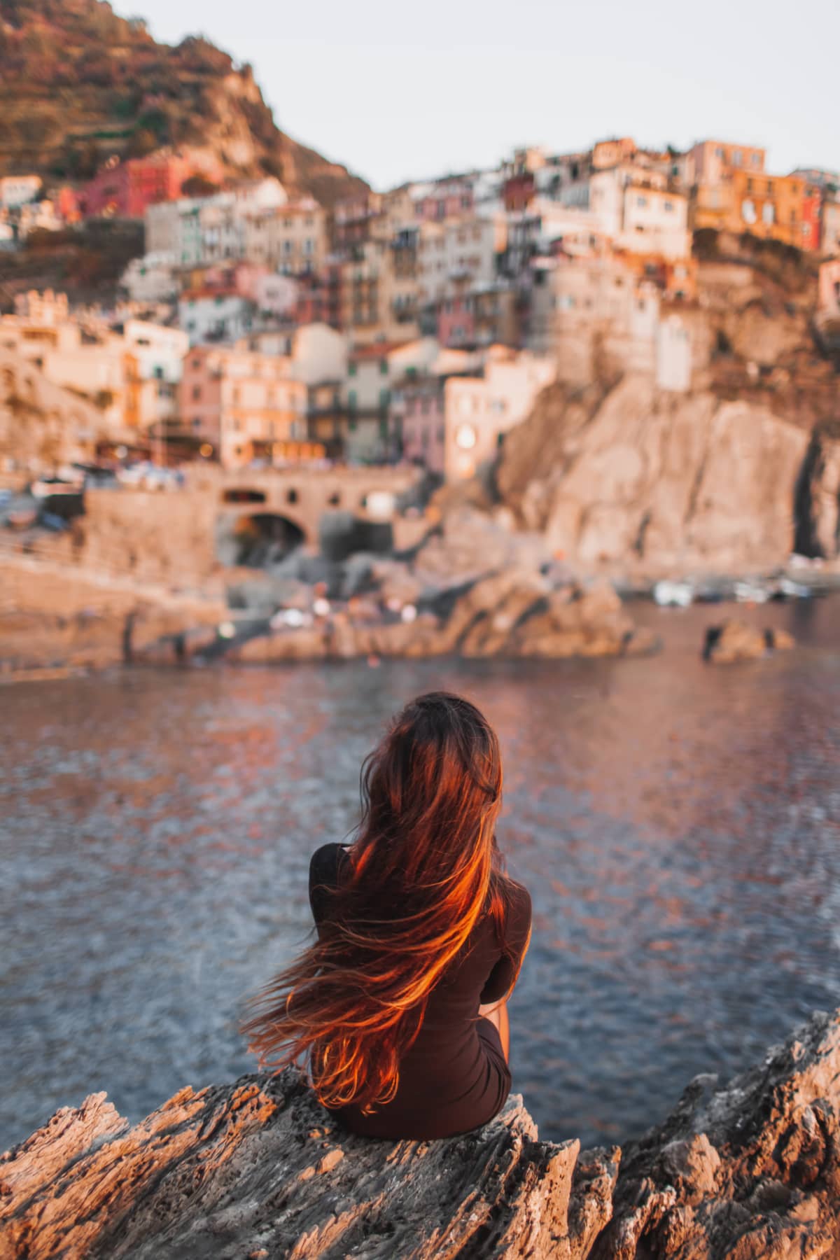 Woman traveling alone enjoys the cliffside view of a nearby town