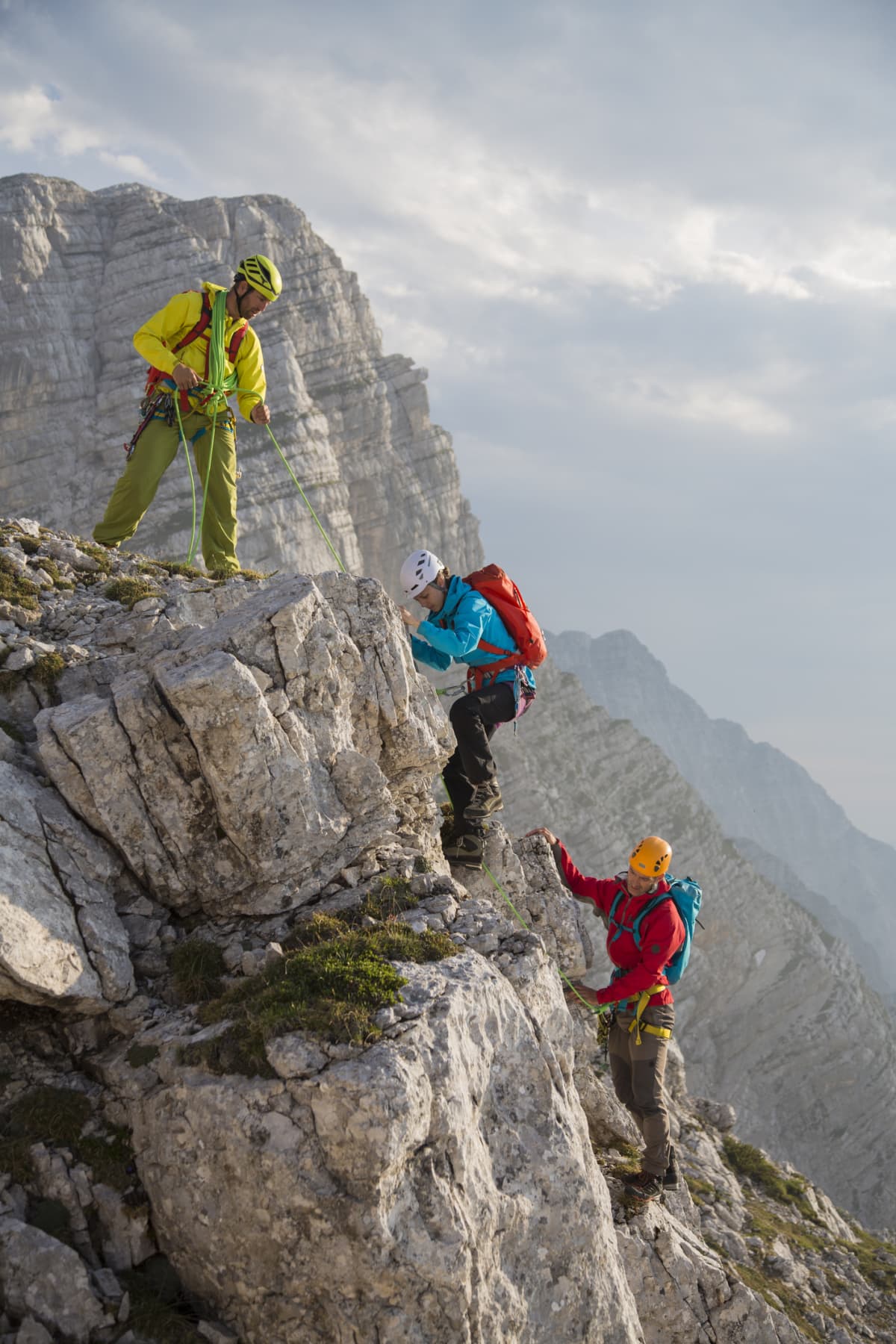 Three men climbing a moutain with fulll gear and backpacks