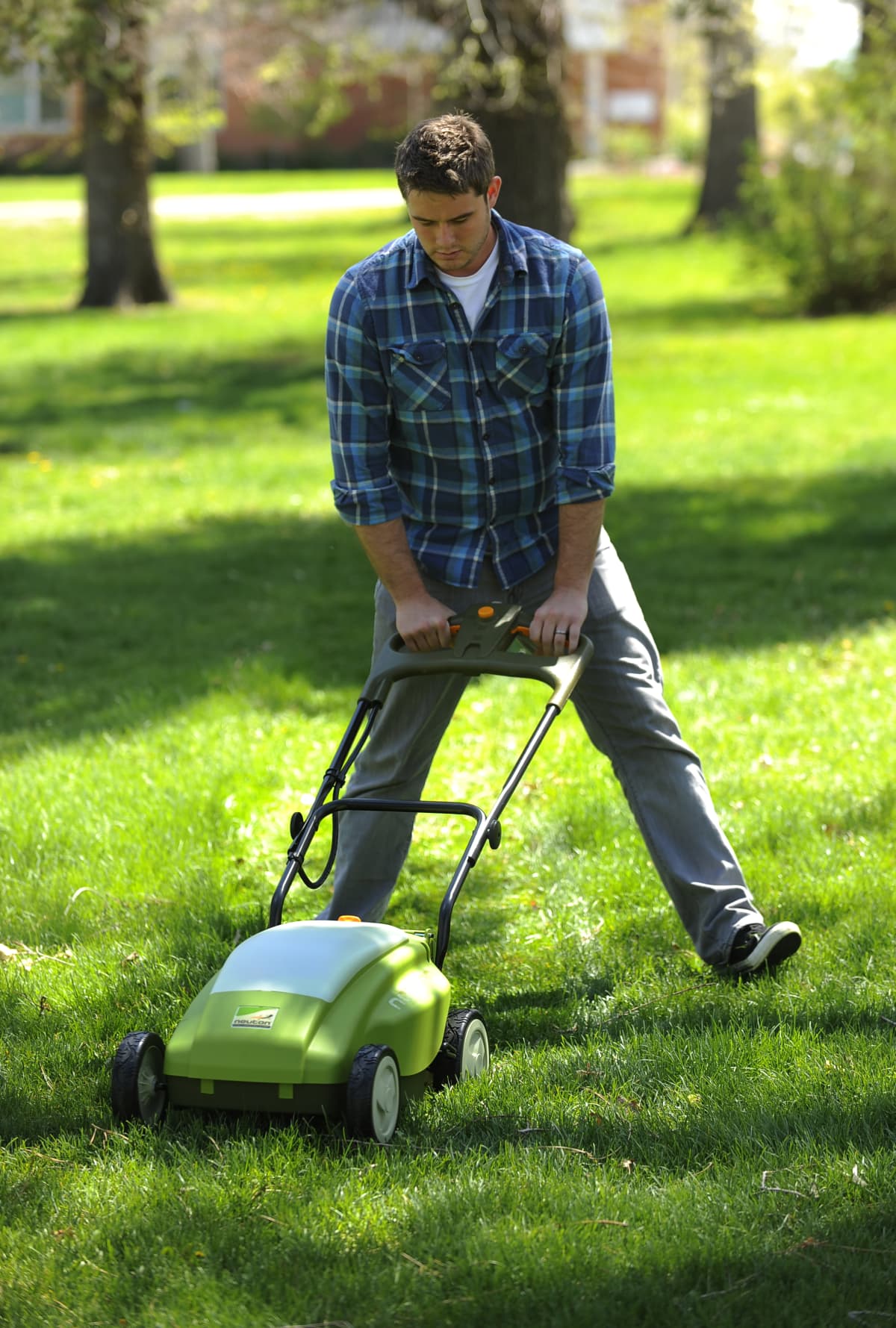 A man operating a battery-powered lawn mower on a green lawn