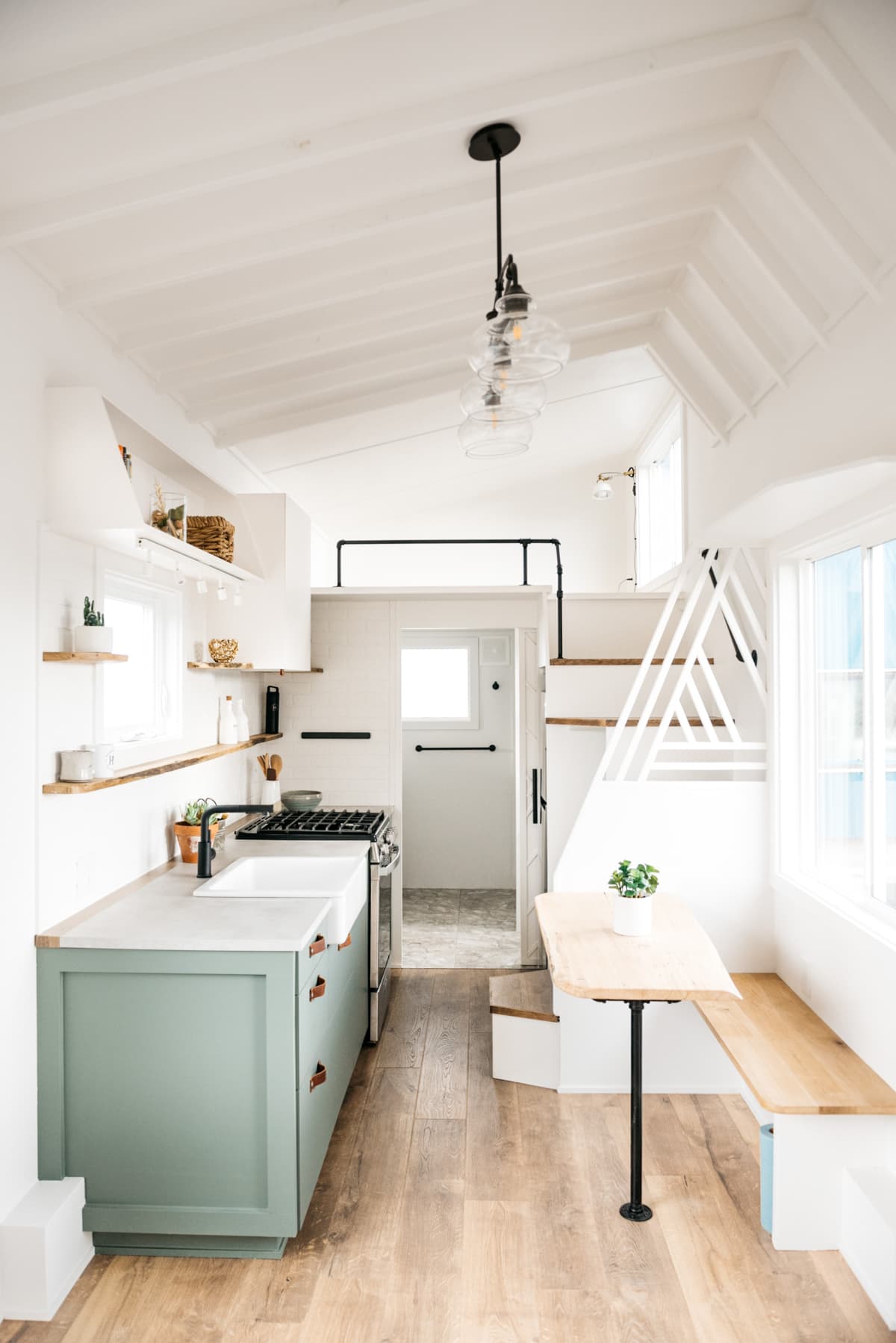 Interior Decor shot of Tiny House on a trailer, featuring a small space kitchen, bedroom, and bathroom.