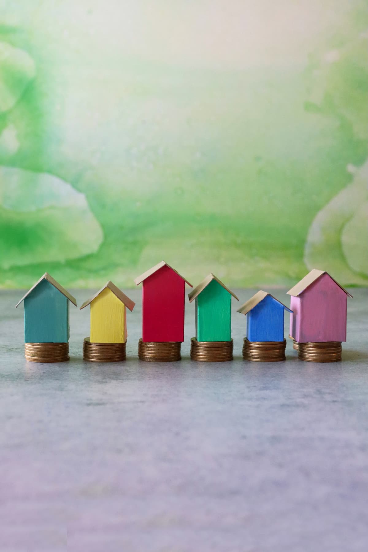 A row of multicolored cardboard houses on stacks of coins