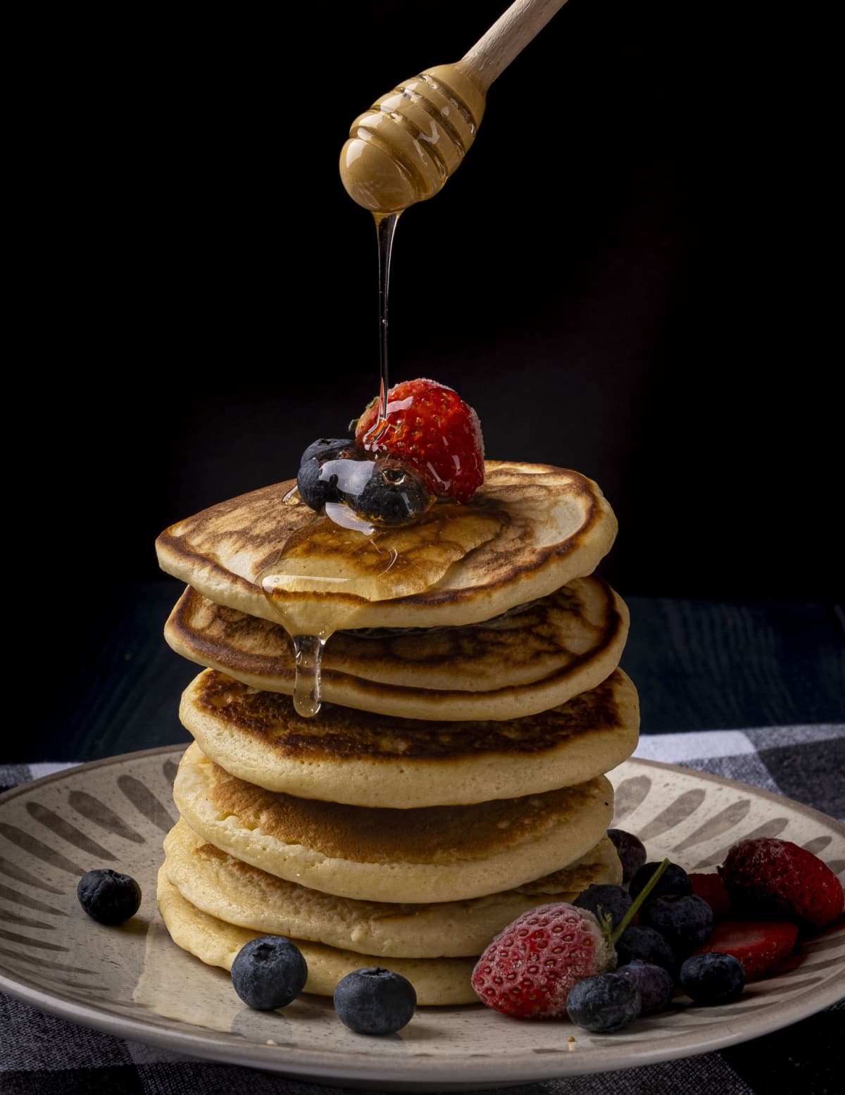 Honey Pancakes with fruit on a black background.