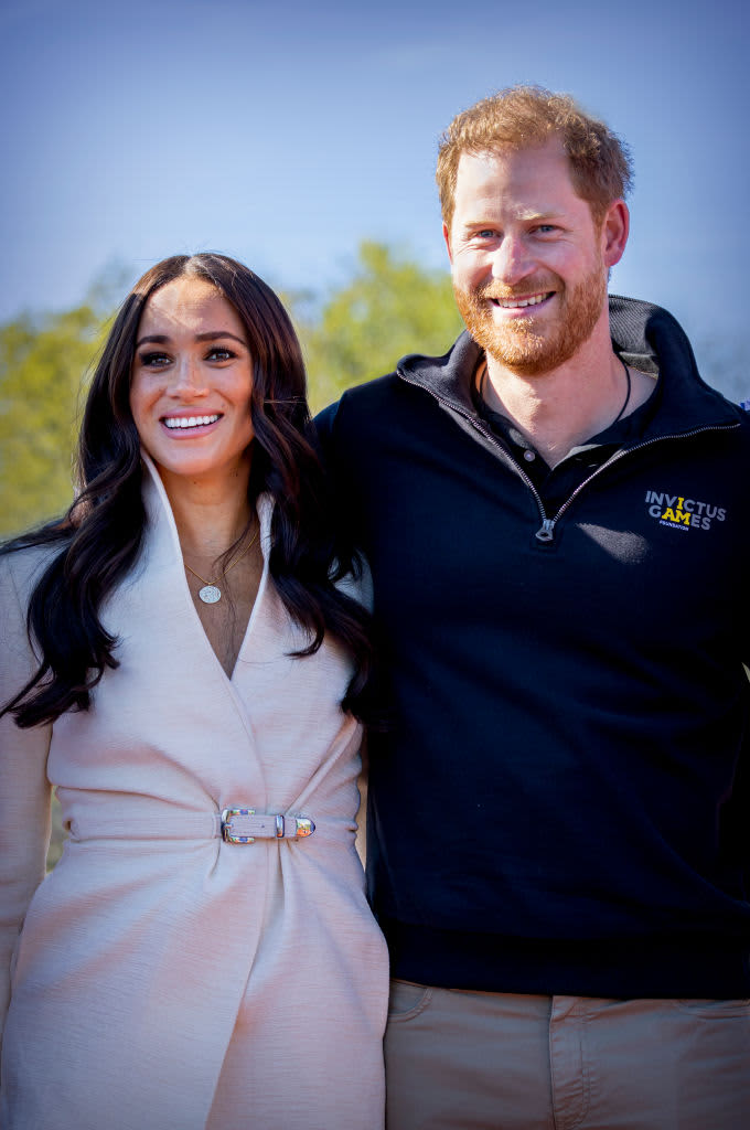 Prince Harry and Meghan Markle smile for the cameras with their arms around one another at the Invictus Games