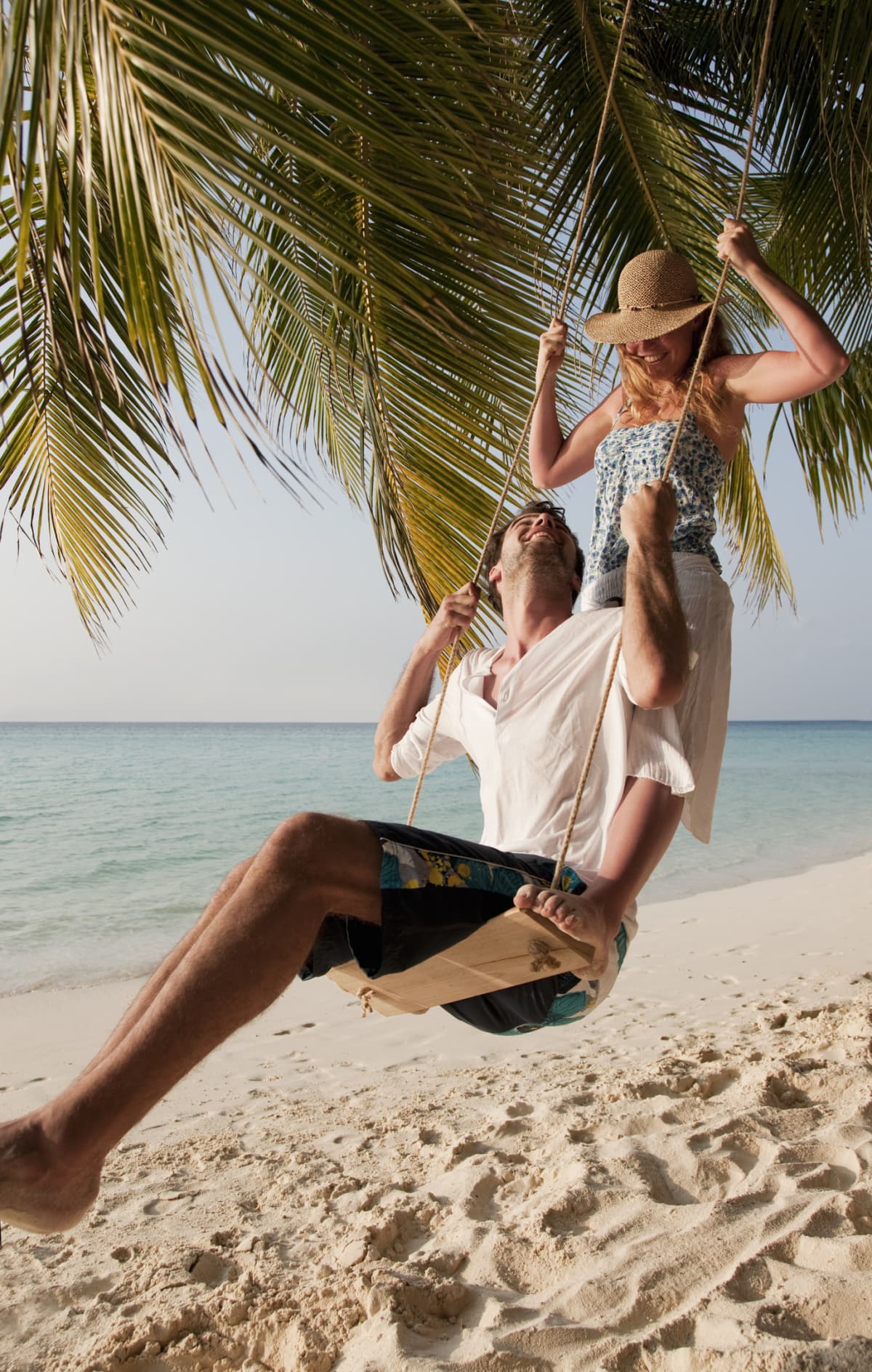 A couple on a tree swing at a beach