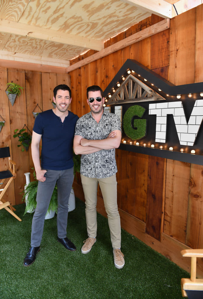 The Property Brothers posing next to an HGTV logo