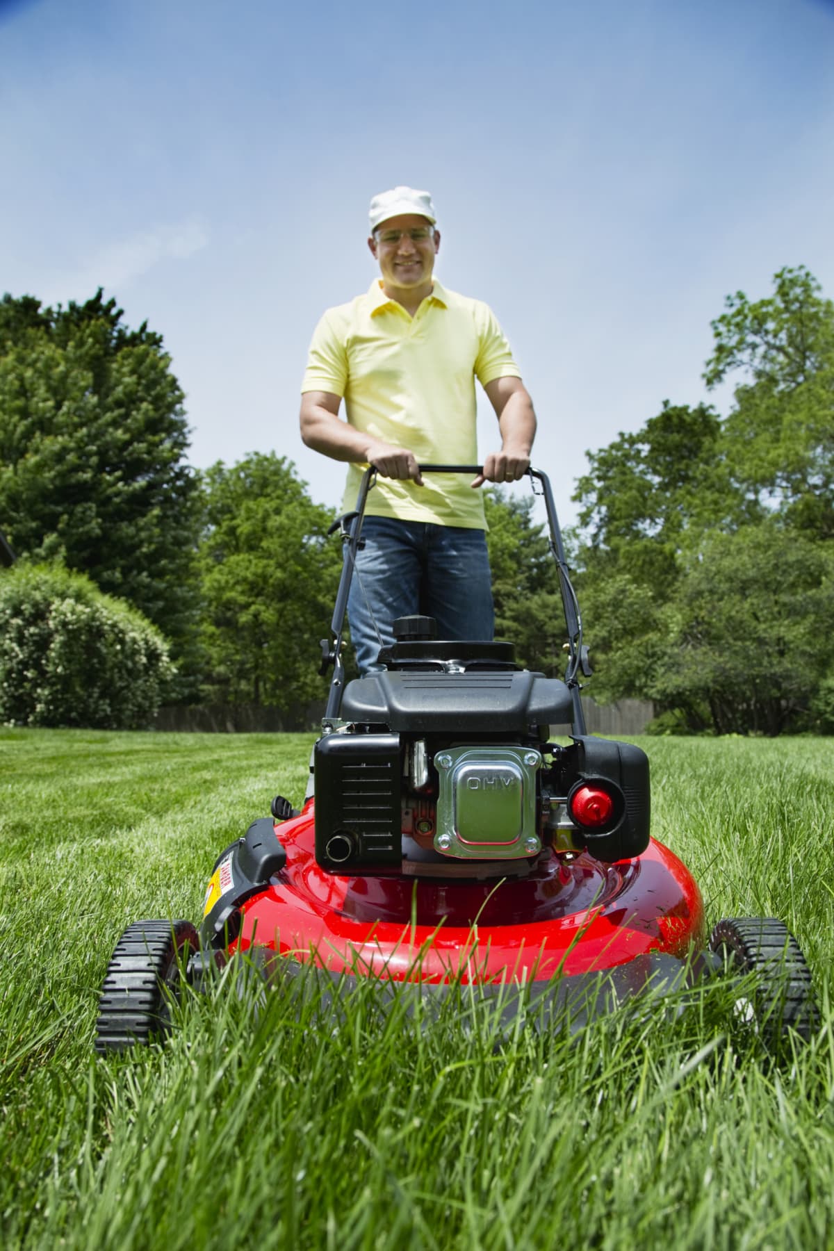 A man pushing a lawn mower towards the camera