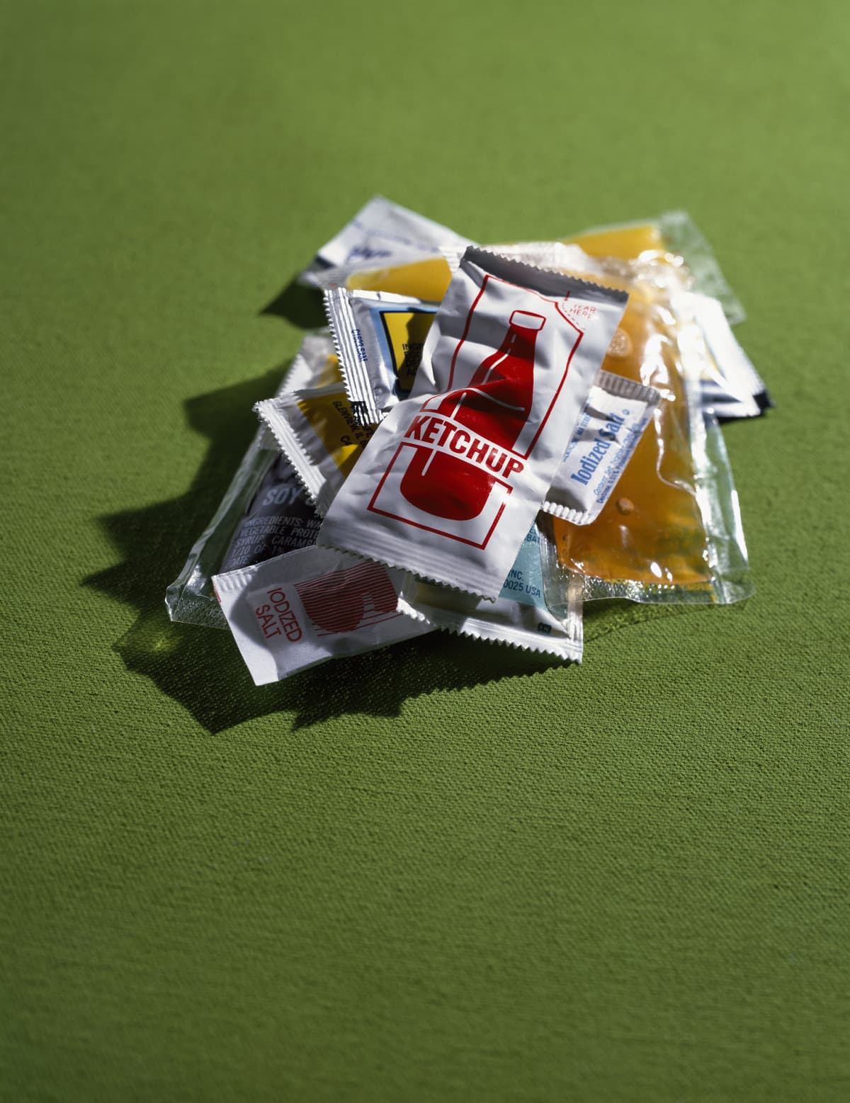 Sauce packets against a green background.