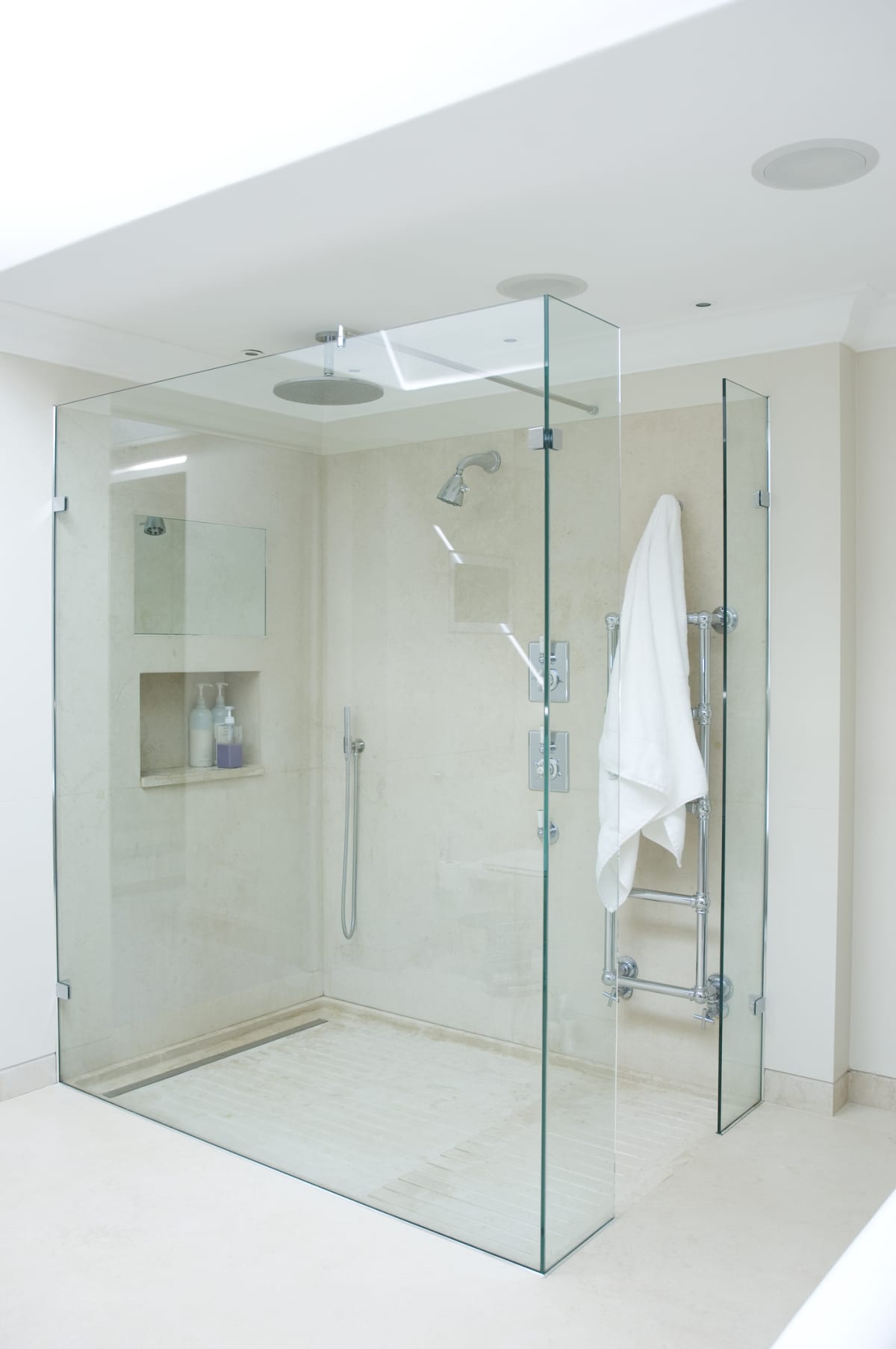 A walk-in shower with glass walls and a linear shower drain