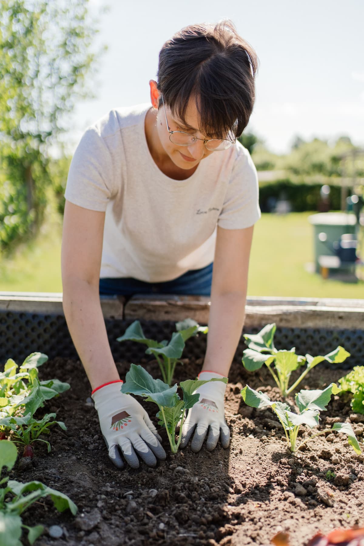 Young gardener wearing gloves and working in a raised garden bed