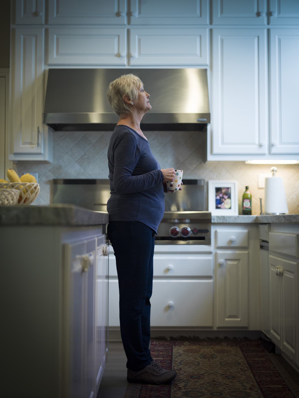 Older woman holding coffee cup in kitchen