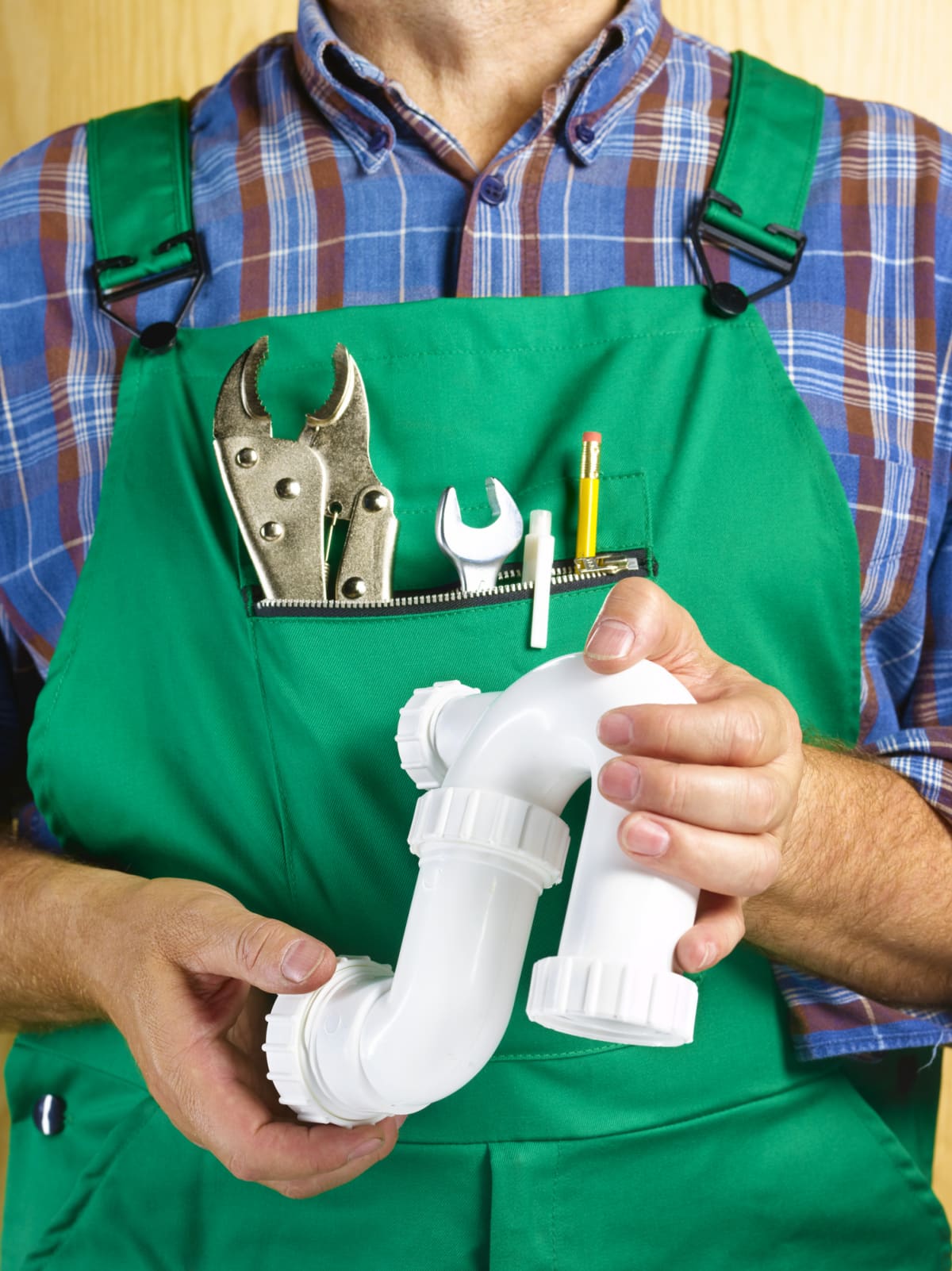 Close up of a plumber with tools in his green overalls
