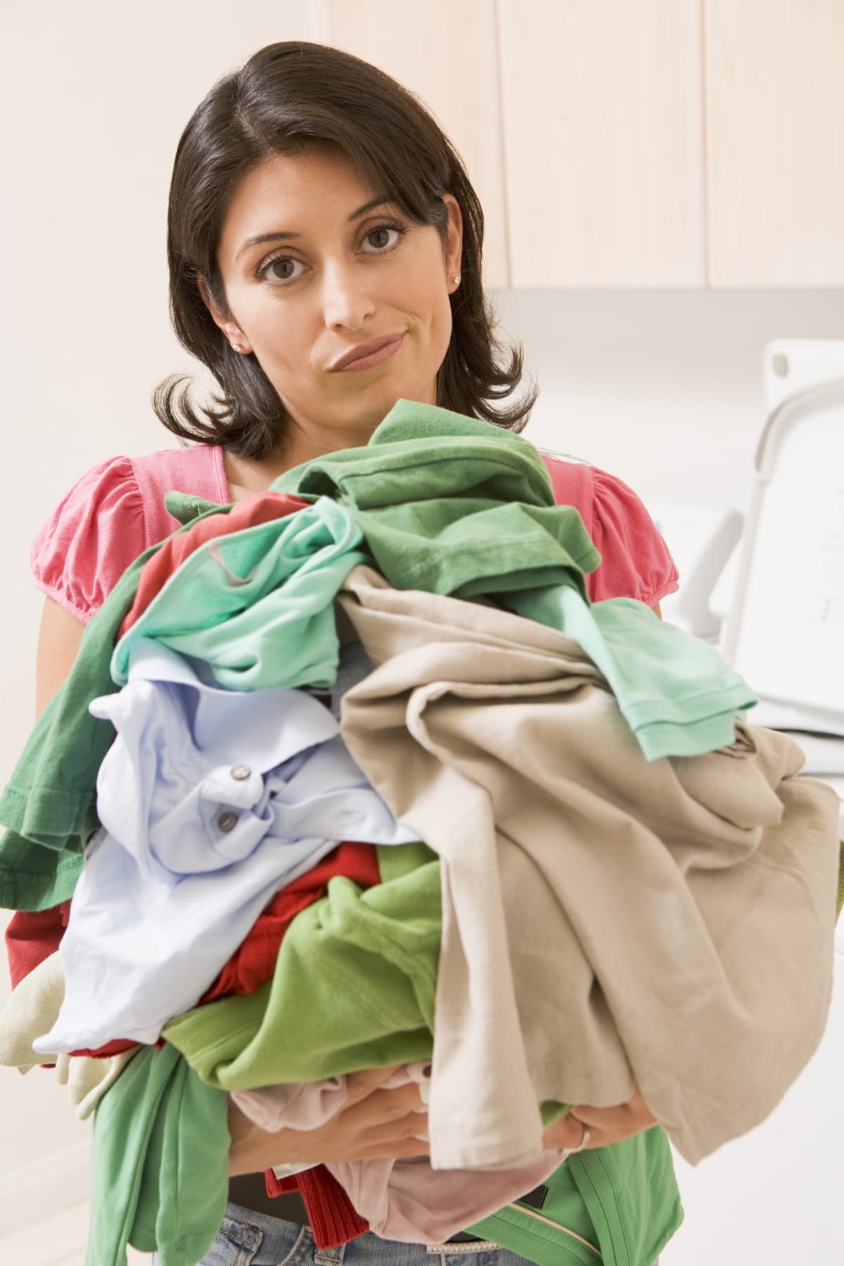 A frowning woman holding an armful of laundry