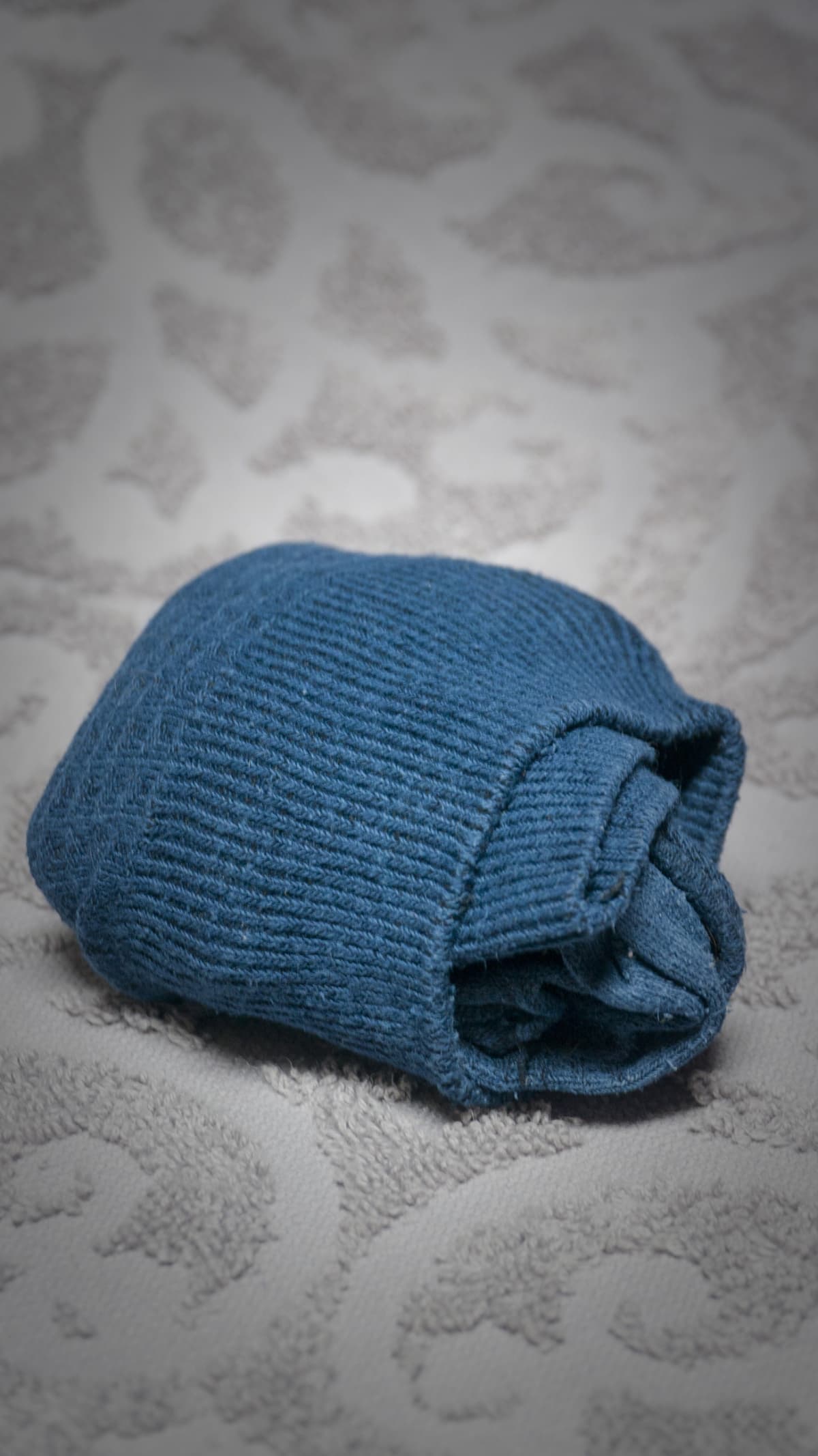 Pair of blue socks folded in the shape of a ball on a grey textile background with relief
