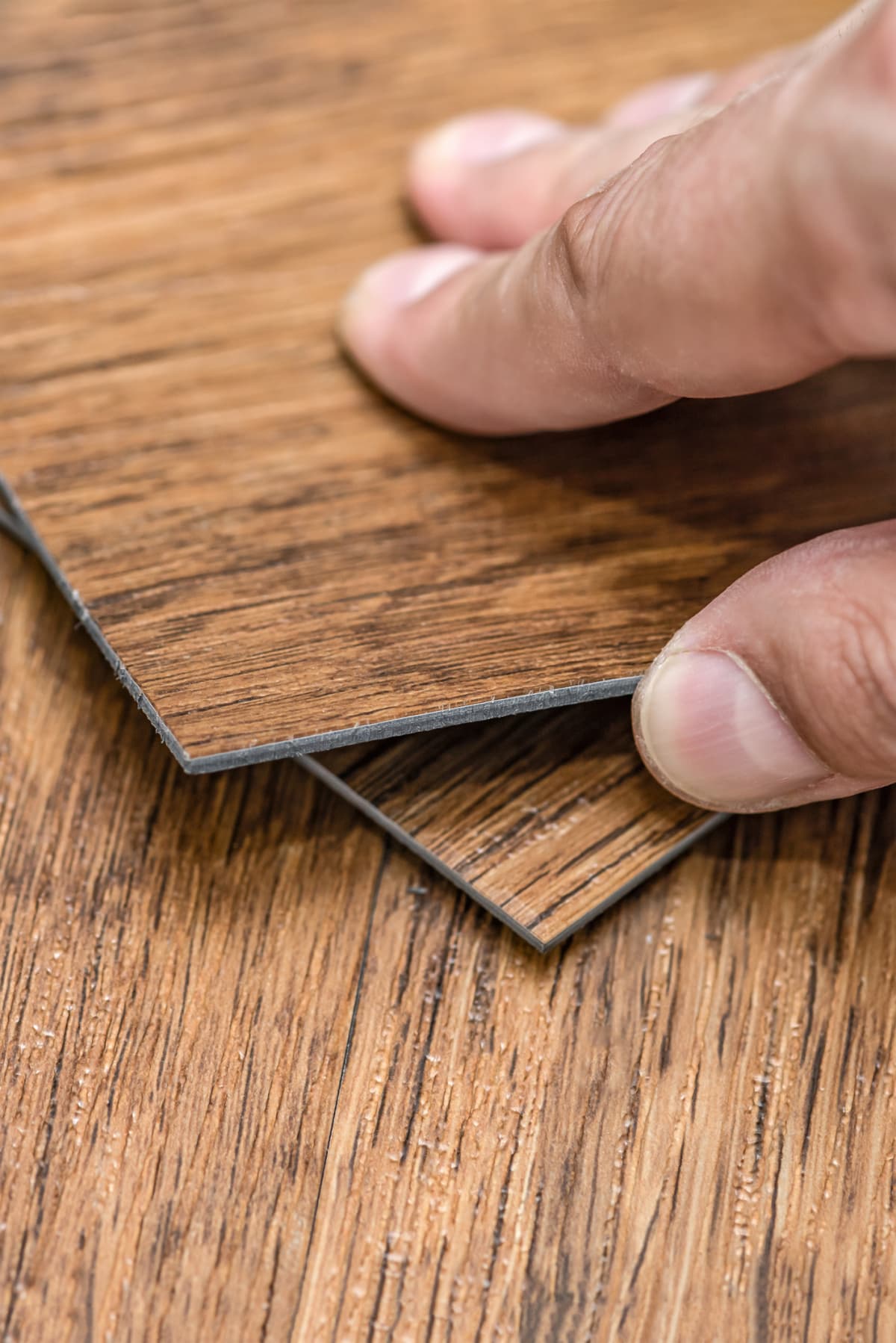 A person holding a textured vinyl floor tile